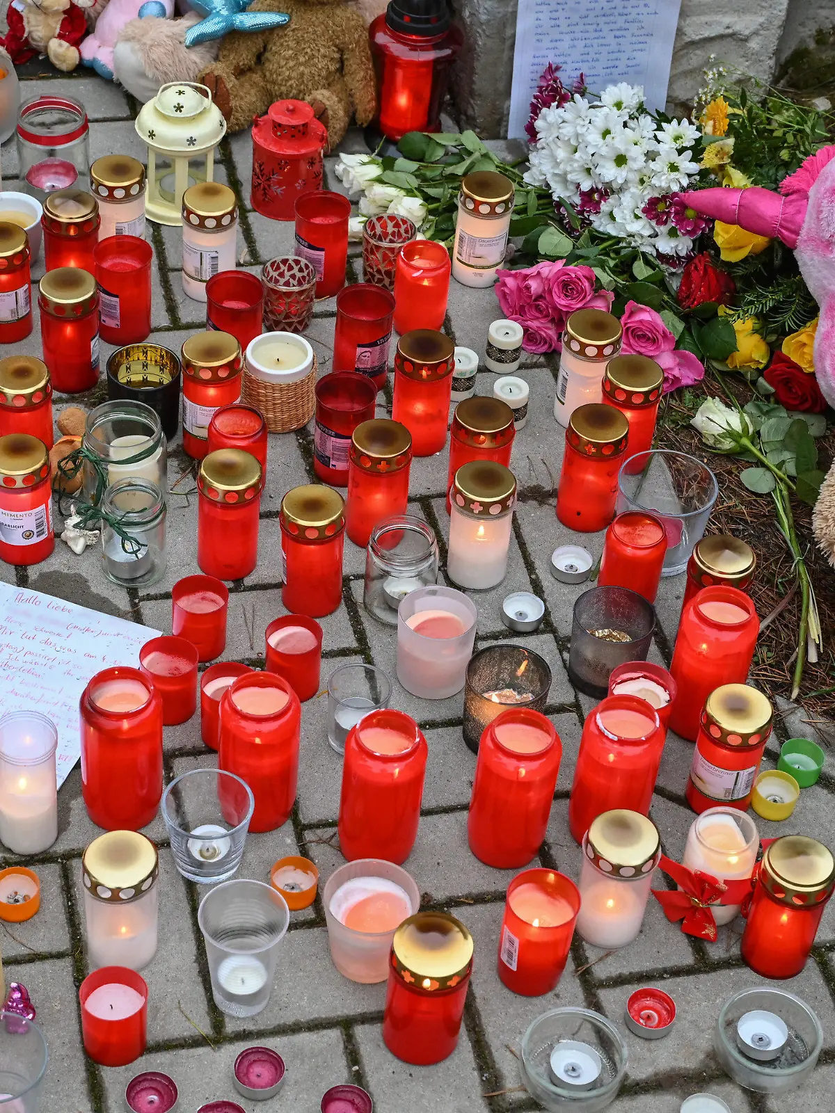 06.12.2021, Brandenburg, Senzig: Viele Kerzen brennen vor auf einem Gehweg vor einem Einfamilienhaus in einem Ortsteil der Stadt Königs Wusterhausen im Landkreis Dahme-Spreewald. Am 04.12.2021 hatten Zeugen in diesem Einfamilienhaus leblose Personen gesehen und die Polizei alarmiert. Die Beamten fanden die fünf Bewohner des Hauses tot vor. Darunter waren auch drei Kinder im Alter von 4, 8 und 10 Jahren, wie die Staatsanwaltschaft Cottbus und die Polizeidirektion Süd in einer gemeinsam Presseerklärung mitteilten. Die beiden Erwachsenen seien 40 Jahre alt gewesen. Foto: Patrick Pleul/dpa-Zentralbild/dpa - ACHTUNG: Namen wurden aus rechtlichen Gründen gepixelt +++ dpa-Bildfunk +++