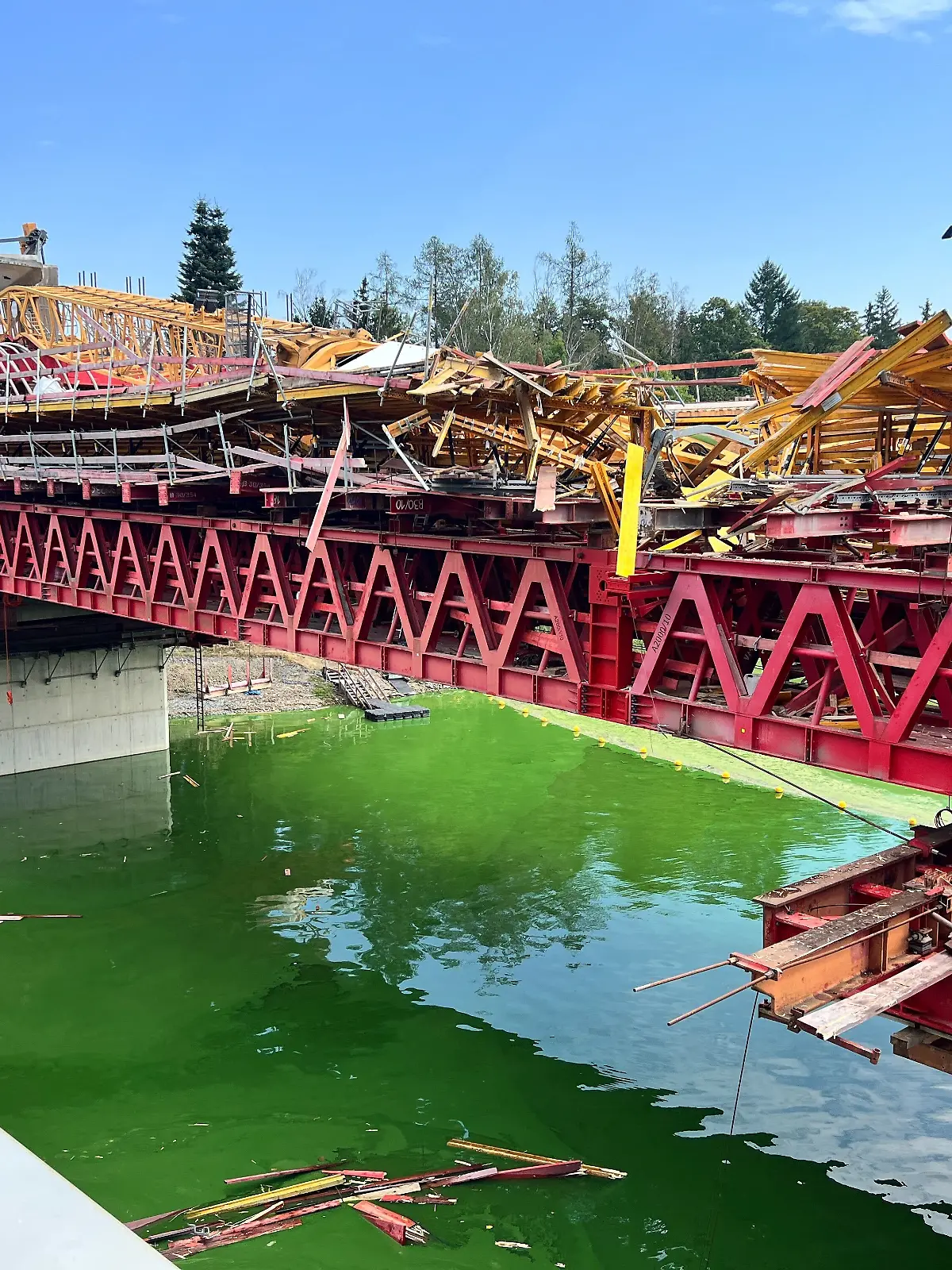 Ein umgestürzter Kran liegt auf einer Brücke, die sich im Bau befindet. 