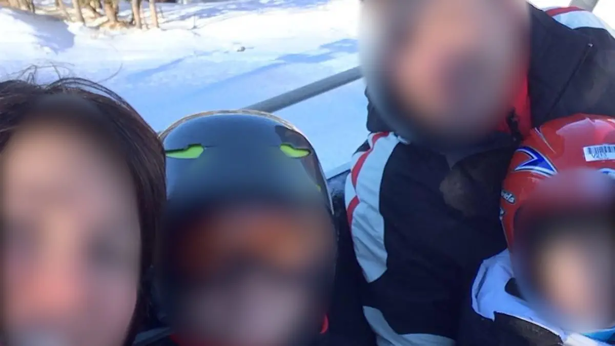 Die Familie ist im Skiurlaub. In Skisachen schauen sie in die Kamera. Die Gesichter aller Personen sind unkenntlich gemacht.