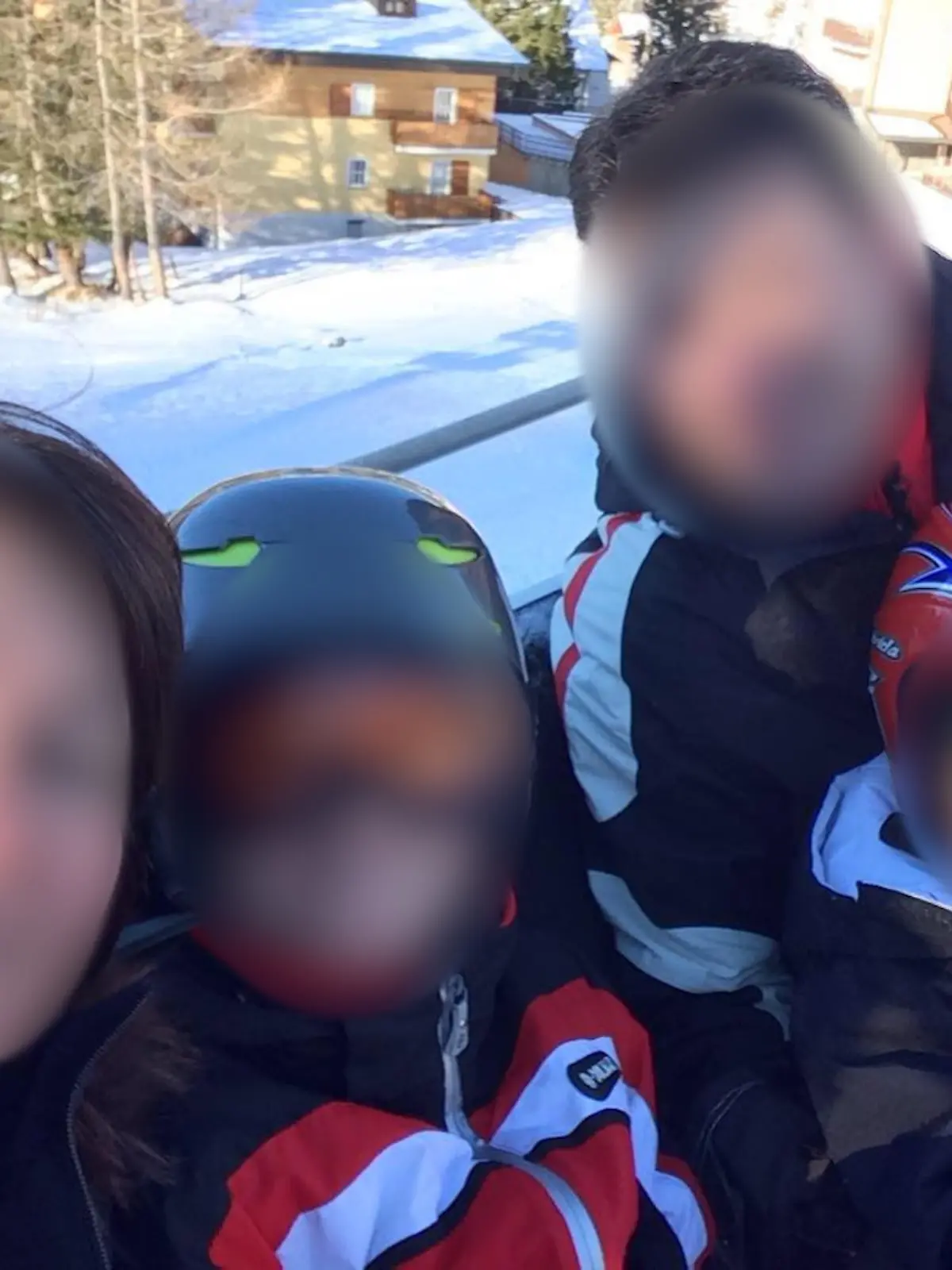 Die Familie ist im Skiurlaub. In Skisachen schauen sie in die Kamera. Die Gesichter aller Personen sind unkenntlich gemacht.