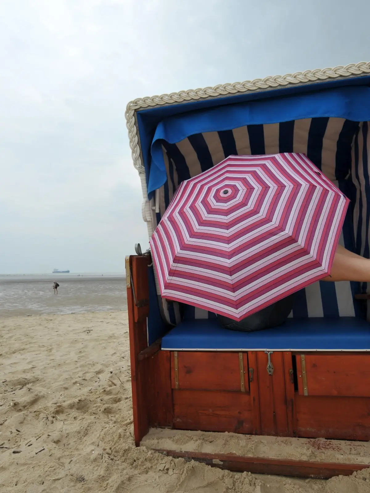 Eine junge Frau sitzt am Sonntag (04.09.2011) mit einem Regenschirm geschützt in einem Korb am Strand von Döse bei Cuxhaven. Mal Wolken, mal Sonne - mit beidem ist beim Wetter in den nächsten Tagen zu rechnen. Foto: Carmen Jaspersen dpa/lni