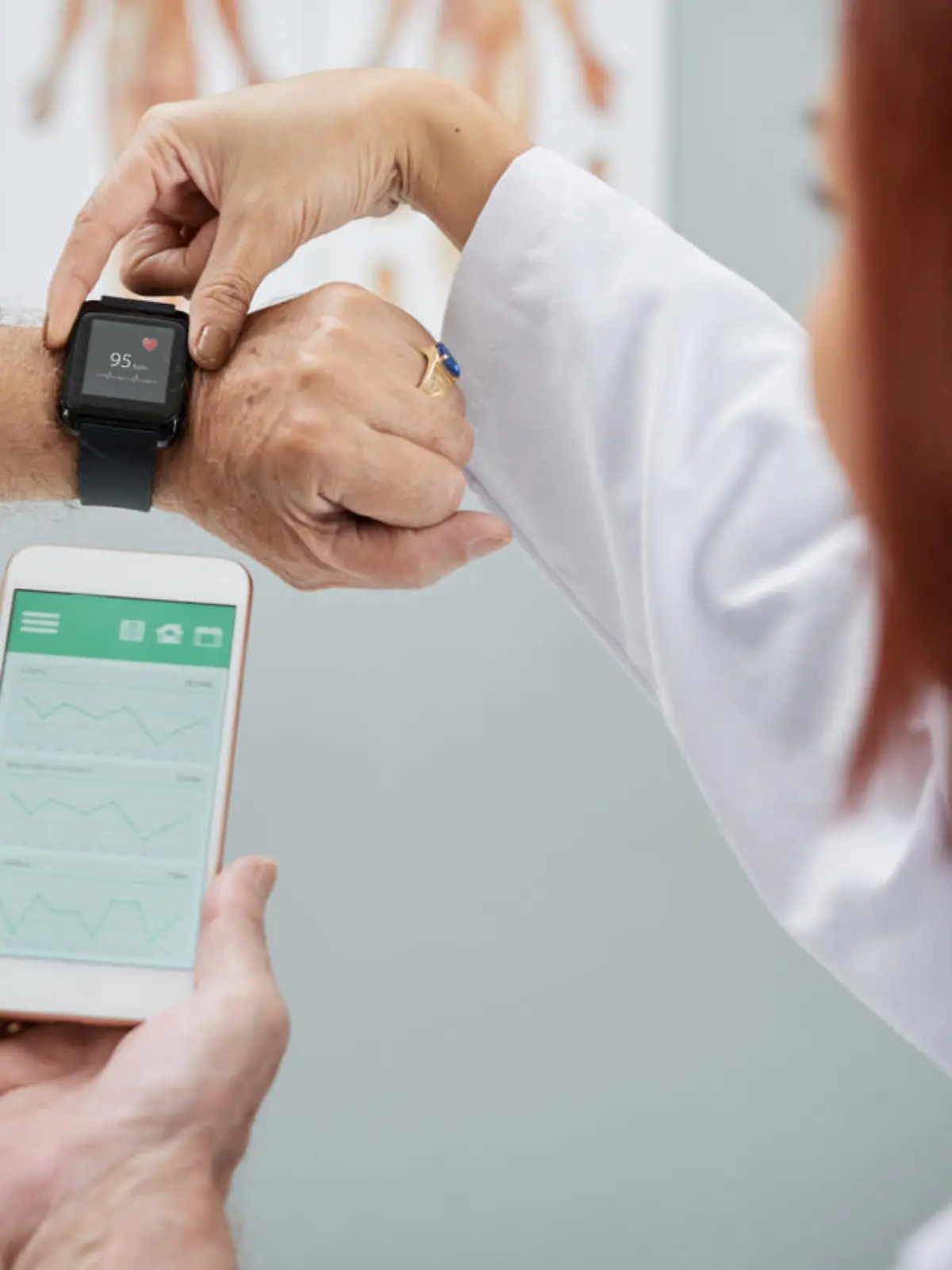 Doctor showing senior patient how to synchronize health app in smartphone and smartwatch
