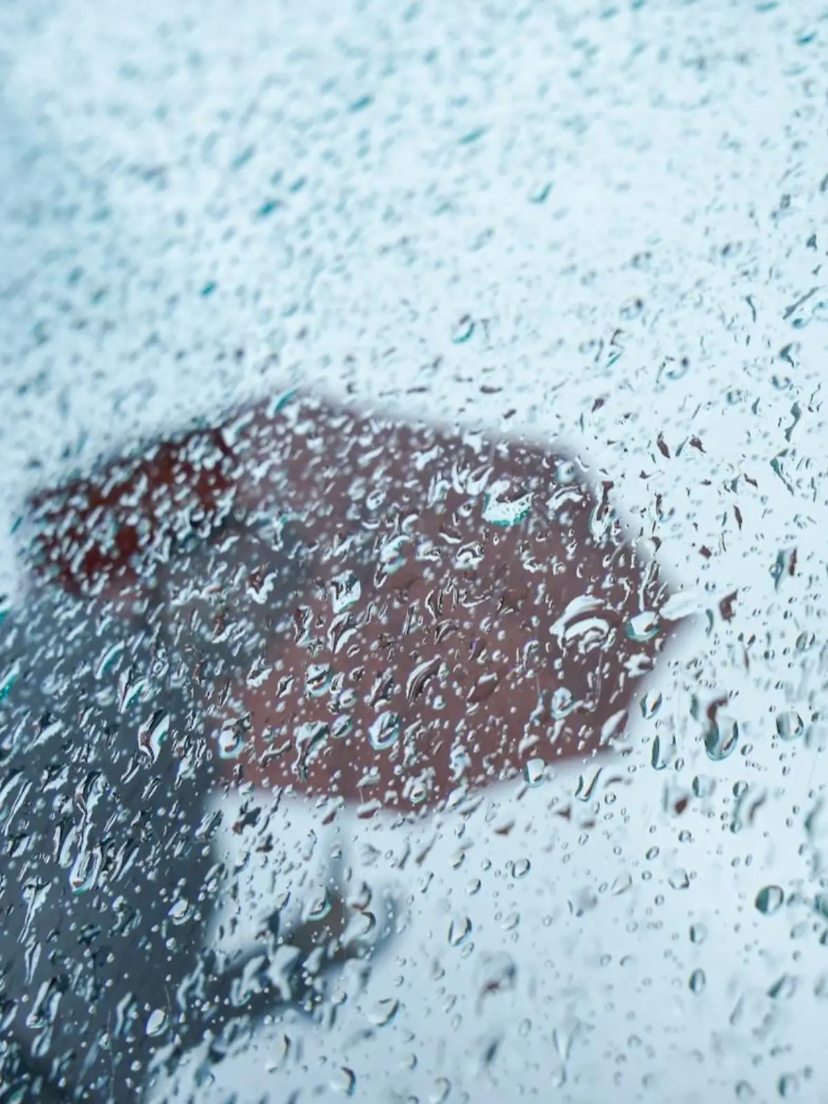 07.10.2023, Hamburg: Eine Passantin geht mit ihrem Regenschirm an einer Scheibe mit Regentropfen in der Innenstadt vorbei. Für heute sind weitere Regenschauer vorhergesagt. Foto: Marcus Brandt/dpa +++ dpa-Bildfunk +++