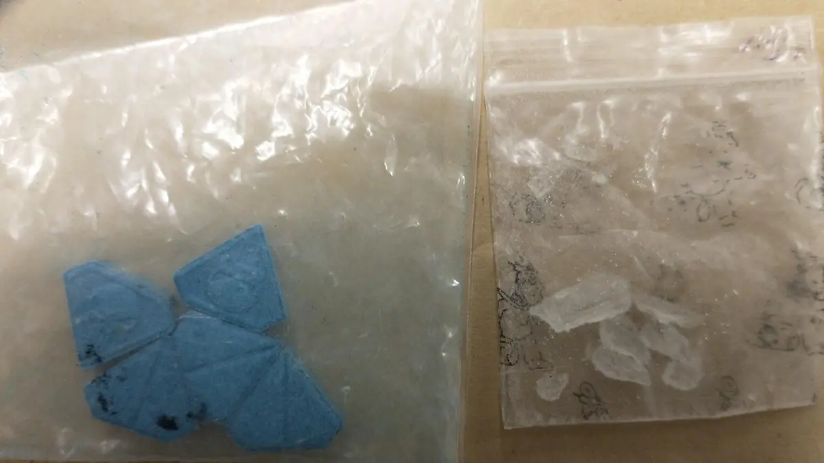 Zwei durchsichtige Druckverschlusstütchen mit blauen Ecstasy Pillen der Sorte "Blue Punisher". Daneben ein weiteres Tütchen mit Kristallen - vermutlich Crystal Meth.