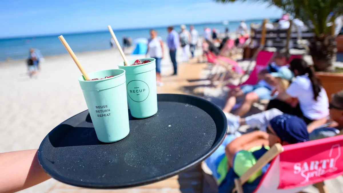 PRODUKTION - 29.05.2023, Schleswig-Holstein, Scharbeutz: Getränke stehen auf dem Tablett einer Kellnerin der Beachlounge Scharbeutz am Ostseestrand. Seit einigen Jahren breitet sich an den Ostseestränden ein neuer Trend aus. Strandbars bieten ihren Gästen kühle Getränke, bunte Cocktails und leckere Speisen an. Und ein unbeschwertes Urlaubsgefühl mit den Füßen im Sand. Foto: Jonas Walzberg/dpa +++ dpa-Bildfunk +++