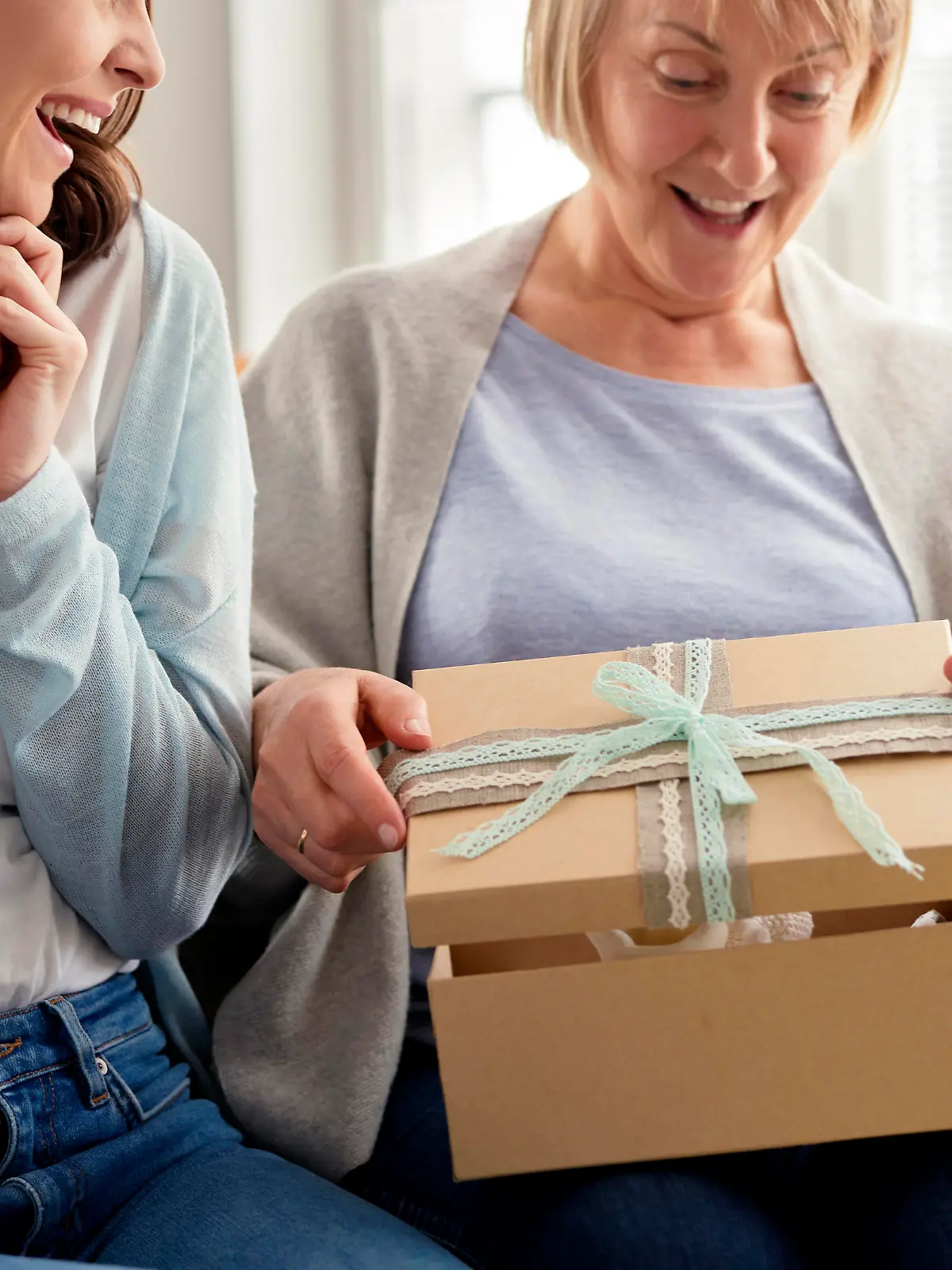                                 Excited adult daughter waiting for mom to open the gift