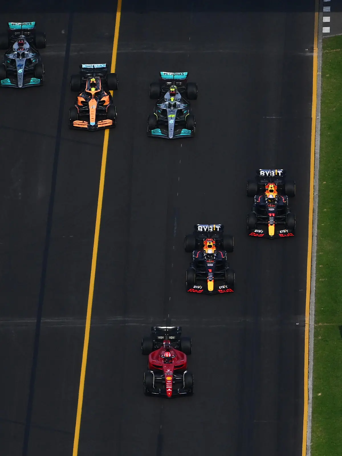 MELBOURNE, AUSTRALIA - APRIL 10: Charles Leclerc of Monaco driving (16) the Ferrari F1-75 leads Max Verstappen of the Netherlands driving the (1) Oracle Red Bull Racing RB18, Sergio Perez of Mexico driving the (11) Oracle Red Bull Racing RB18, Lewis Hamilton of Great Britain driving the (44) Mercedes AMG Petronas F1 Team W13, Lando Norris of Great Britain driving the (4) McLaren MCL36 Mercedes and George Russell of Great Britain driving the (63) Mercedes AMG Petronas F1 Team W13 at the start during the F1 Grand Prix of Australia at Melbourne Grand Prix Circuit on April 10, 2022 in Melbourne, Australia. (Photo by Clive Mason/Getty Images)