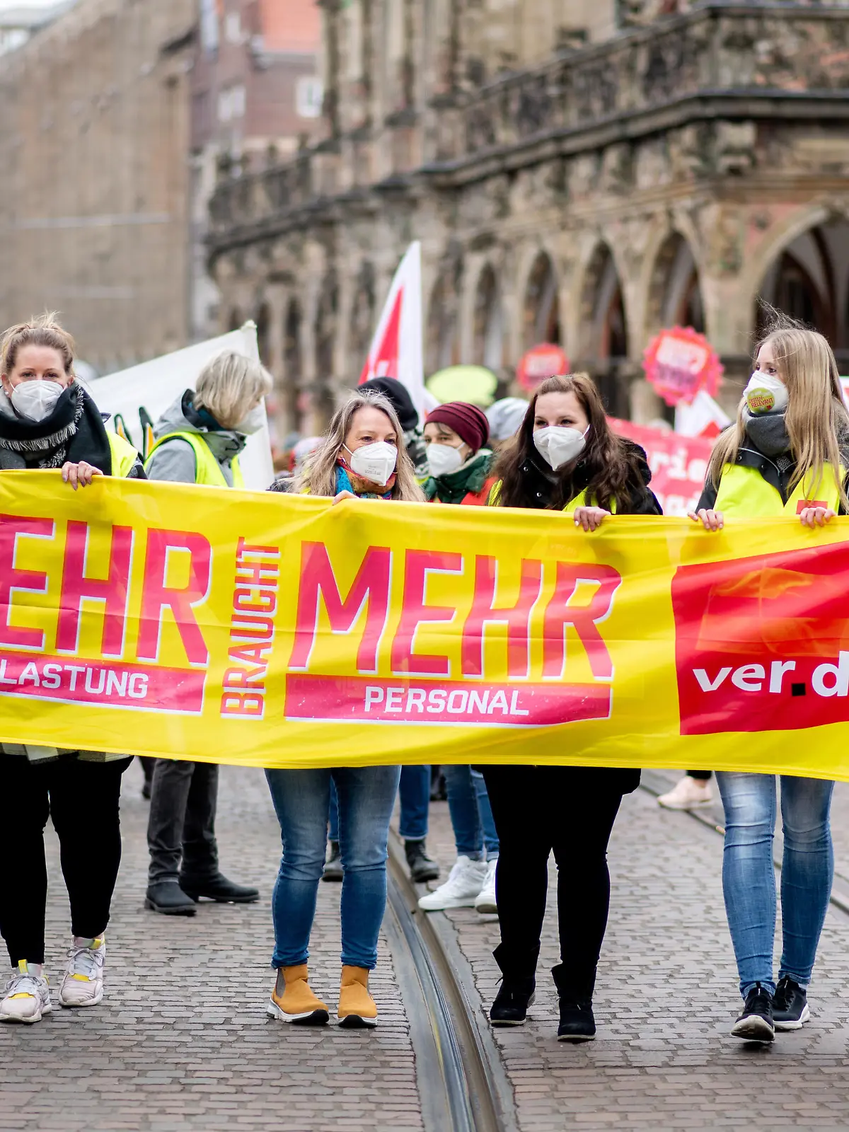 Mitarbeiterinnen und Mitarbeiter kommunaler Kitas und sozialer Dienste gehen während einer Kundgebung mit einem Transparent mit der Aufschrift „Mehr braucht mehr“ über den Marktplatz. Zahlreiche Beschäftigte der kommunalen Kitas und sozialer Dienste in Niedersachsen und Bremen haben die Arbeit niedergelegt. Sie folgten dem Aufruf der Gewerkschaft Verdi zu einem ganztägigen Warnstreik, um in den laufenden Tarifverhandlungen Druck auf die Arbeitgeber auszuüben.