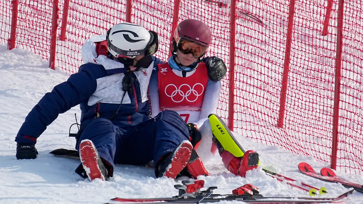 A team member consoles Mikaela Shiffrin, of the United States after she skied out in the first run of the women's slalom at the 2022 Winter Olympics, Wednesday, Feb. 9, 2022, in the Yanqing district of Beijing. (AP Photo/Robert F. Bukaty)