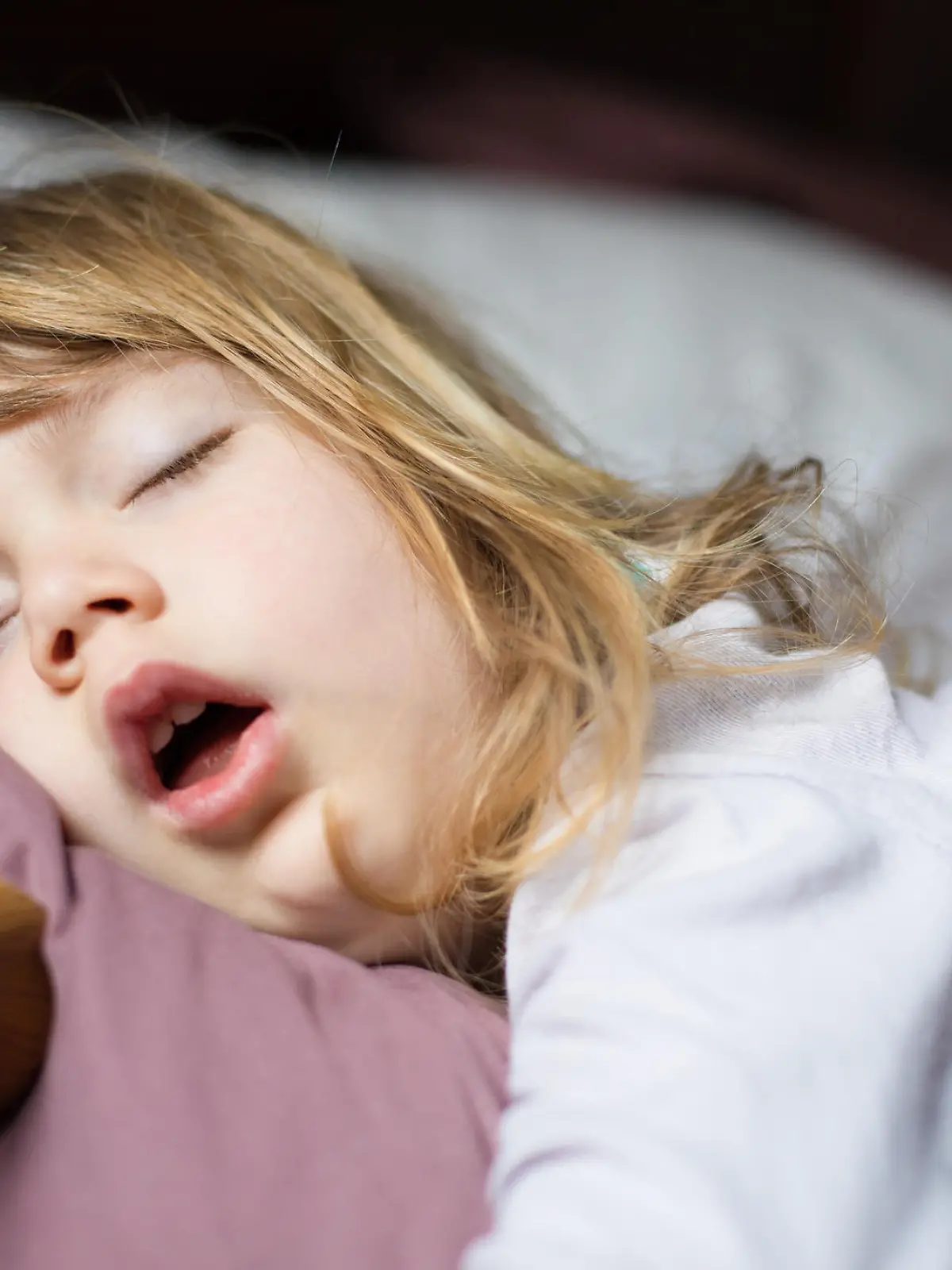 funny face expression with open mouth of blonde caucasian three years old child,  sleeping on  king bed