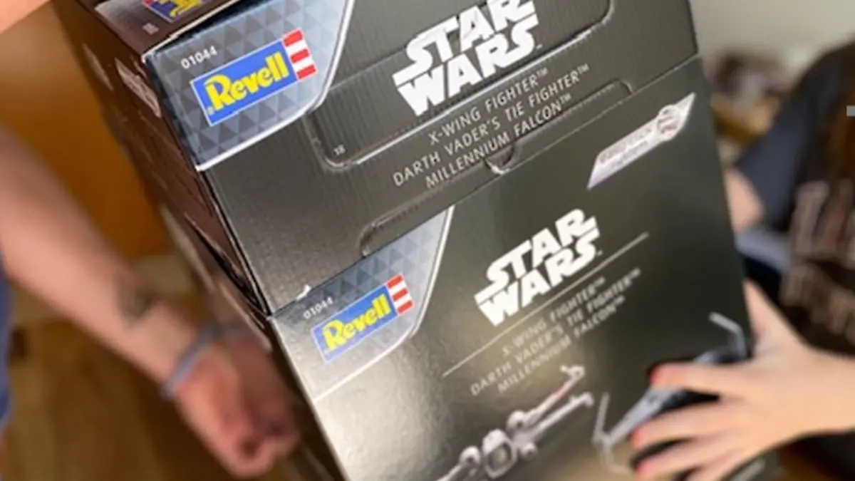 Männerhände und Kinderhände halten den Star Wars-Adventskalender von Revell