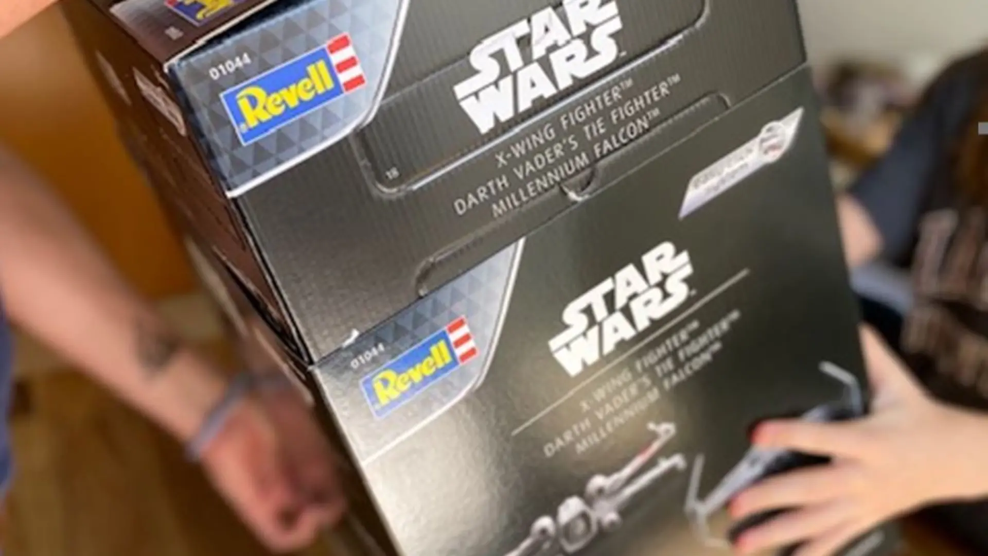 Männerhände und Kinderhände halten den Star Wars-Adventskalender von Revell