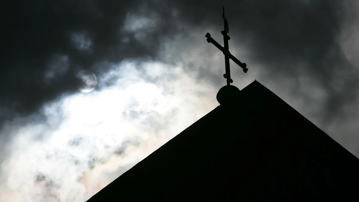 ARCHIV - 18.05.2008, Niedersachsen, Osnabrück: SYMBOLBILD - Im Gegenlicht und vor wolkenverhangenem Himmel ist die Kirchturmspitze des Doms mit Kreuz zu sehen. (zu dpa ««Spiegel»: Studie beweist massiven Missbrauch in katholischer Kirche» vom 12.09.2018) Foto: Friso Gentsch/dpa +++ dpa-Bildfunk +++
