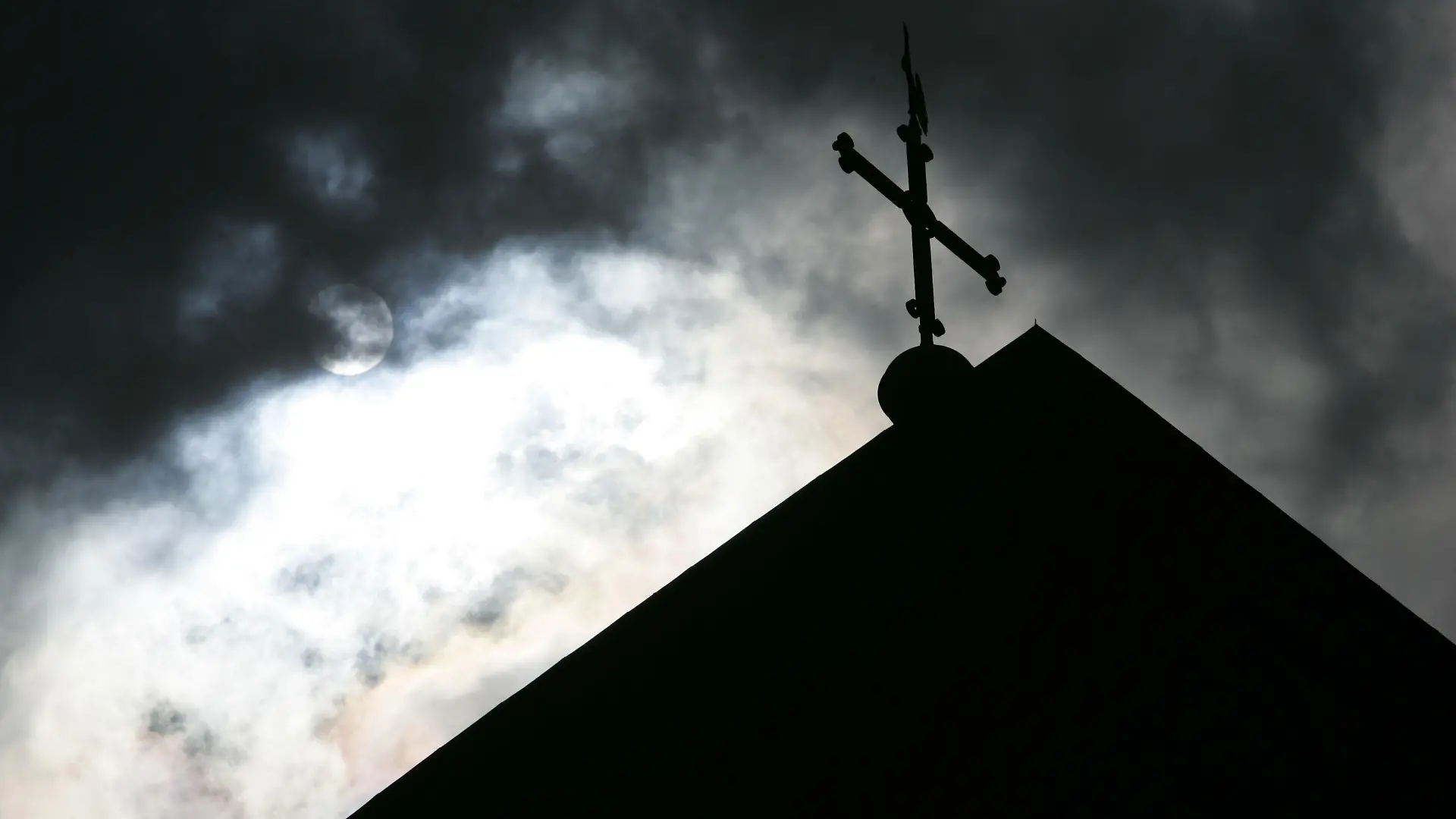 ARCHIV - 18.05.2008, Niedersachsen, Osnabrück: SYMBOLBILD - Im Gegenlicht und vor wolkenverhangenem Himmel ist die Kirchturmspitze des Doms mit Kreuz zu sehen. (zu dpa ««Spiegel»: Studie beweist massiven Missbrauch in katholischer Kirche» vom 12.09.2018) Foto: Friso Gentsch/dpa +++ dpa-Bildfunk +++