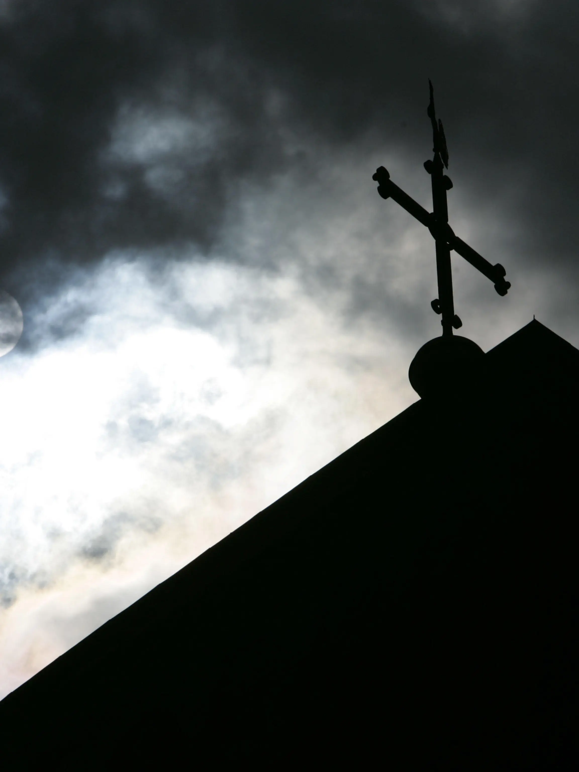 ARCHIV - 18.05.2008, Niedersachsen, Osnabrück: SYMBOLBILD - Im Gegenlicht und vor wolkenverhangenem Himmel ist die Kirchturmspitze des Doms mit Kreuz zu sehen. (zu dpa ««Spiegel»: Studie beweist massiven Missbrauch in katholischer Kirche» vom 12.09.2018) Foto: Friso Gentsch/dpa +++ dpa-Bildfunk +++