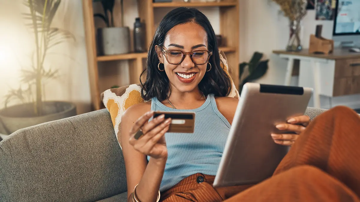 Frau mit Tablet und Kreditkarte auf dem Sofa
