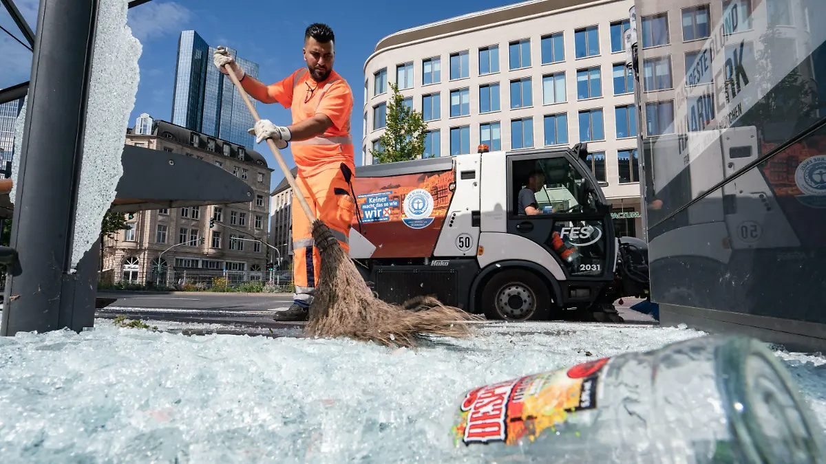 19.07.2020, Hessen, Frankfurt/Main: Mitarbeiter der Stadtreinigung beseitigen am Morgen vor der Alten Oper Scherben der zertrümmerten Scheiben einer Bushaltestelle. In der Nacht zum 19.07.2020 ist es auf dem Opernplatz zu gewalttätigen Krawallen gekommen. Wie die Polizei mitteilte, hatten rund 3000 Menschen Partys gefeiert, als die Randale ausbrachen. 39 Menschen seien daraufhin festgenommen worden, acht davon seien am Sonntagmorgen noch in Gewahrsam gewesen. Foto: Frank Rumpenhorst/dpa +++ dpa-Bildfunk +++