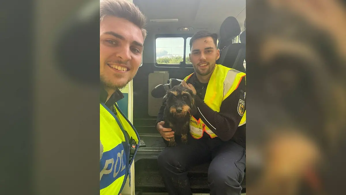 Die Bundespolizisten Marvin Schick (li) und Danny Heineke mit dem geretteten Rauhaardackel.