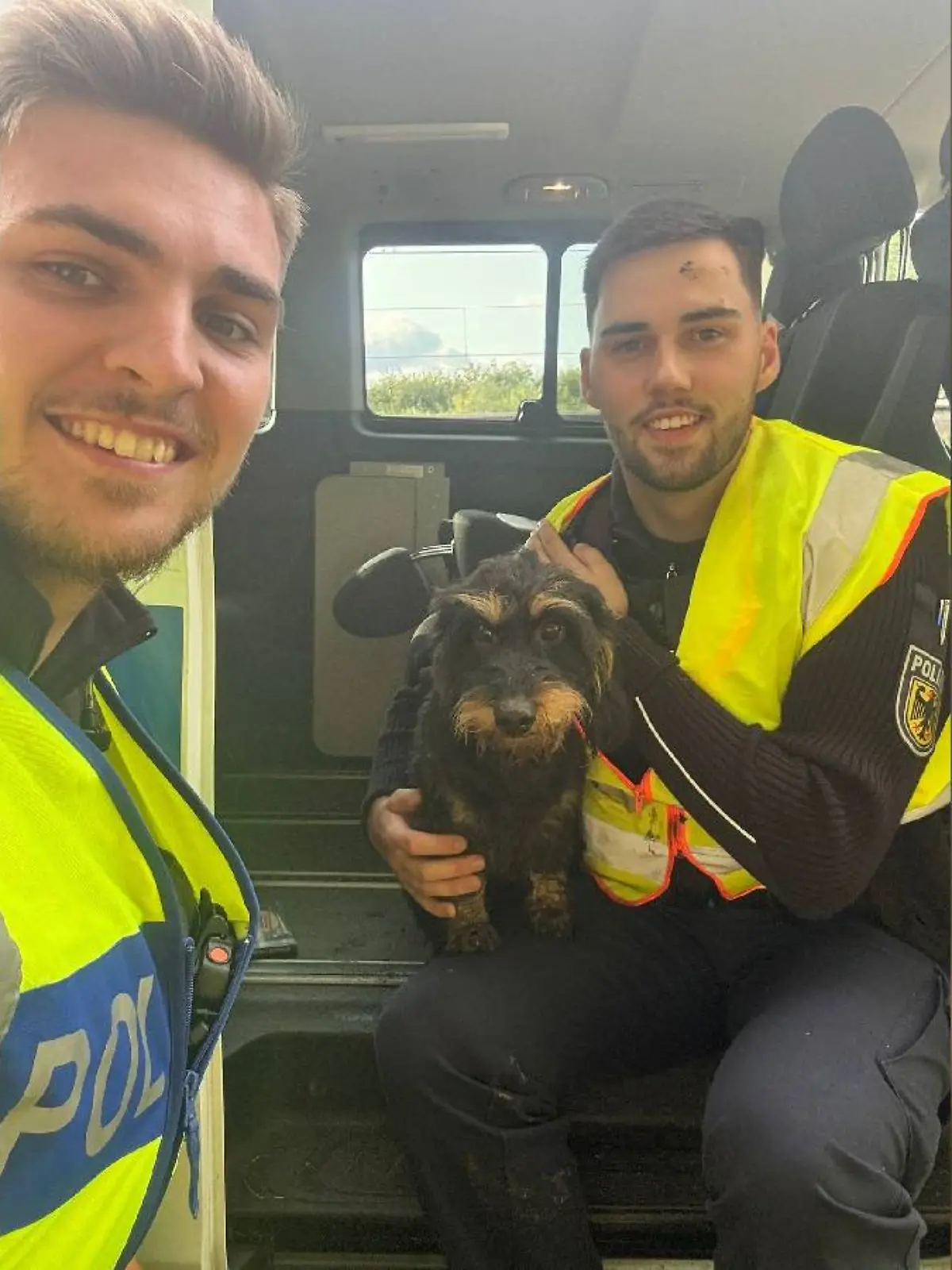 Die Bundespolizisten Marvin Schick (li) und Danny Heineke mit dem geretteten Rauhaardackel.