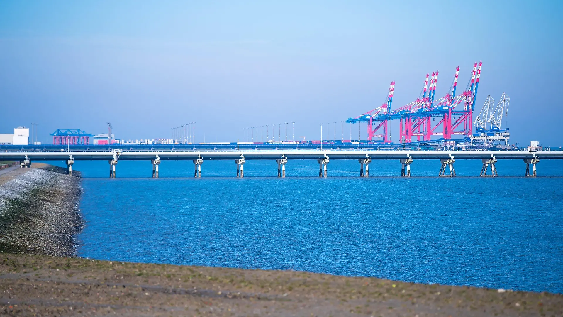 ARCHIV - 28.02.2022, Niedersachsen, Wilhelmshaven: Der Jade-Weser-Port mit den Rohren der Tankerlöschbrücke im Vordergrund. Ein neues Terminal zum Import von Flüssigerdgas (LNG) in Wilhelmshaven soll Deutschland unabhängiger von Gasimporten aus Russland machen - die Deutsche Umwelthilfe hat jetzt allerdings einen sofortigen Baustopp gefordert. (zu dpa: «Umwelthilfe fordert Baustopp am geplanten LNG-Terminal Wilhelmshaven») Foto: Sina Schuldt/dpa +++ dpa-Bildfunk +++