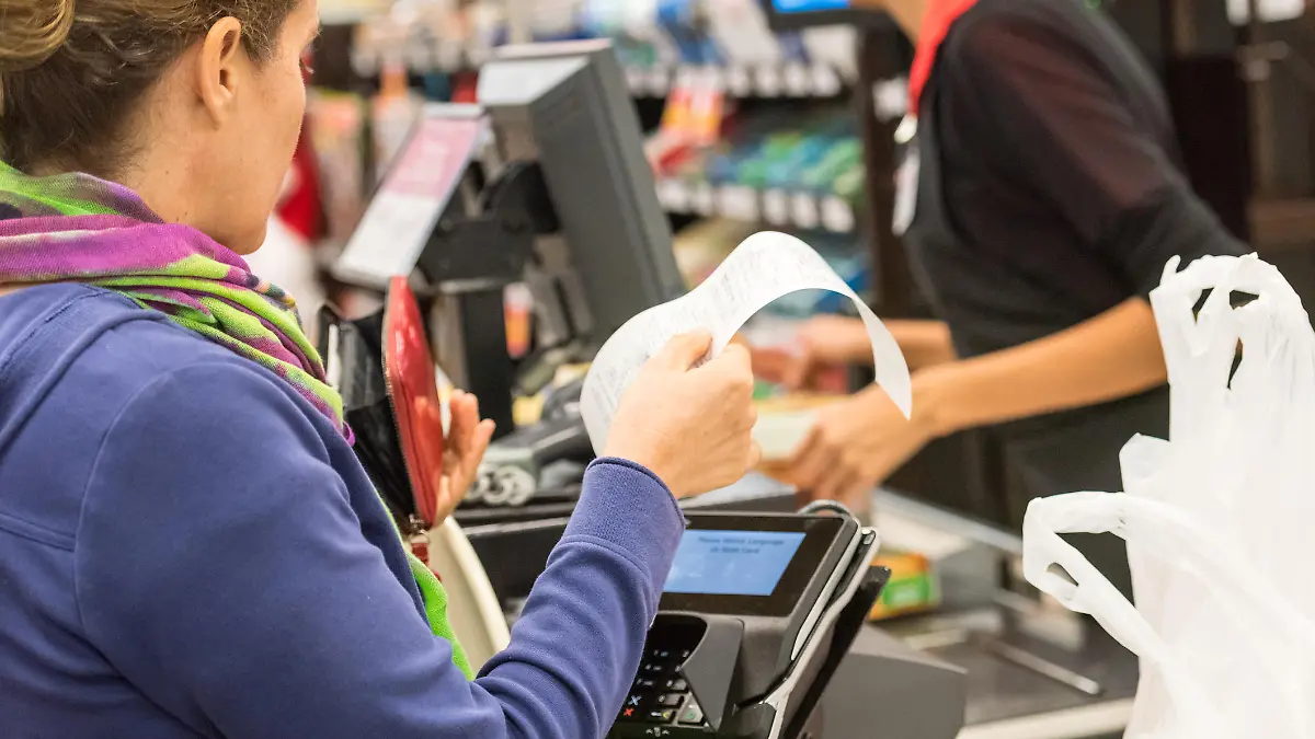 Caucasian woman electronic signing her bill at the supermarket