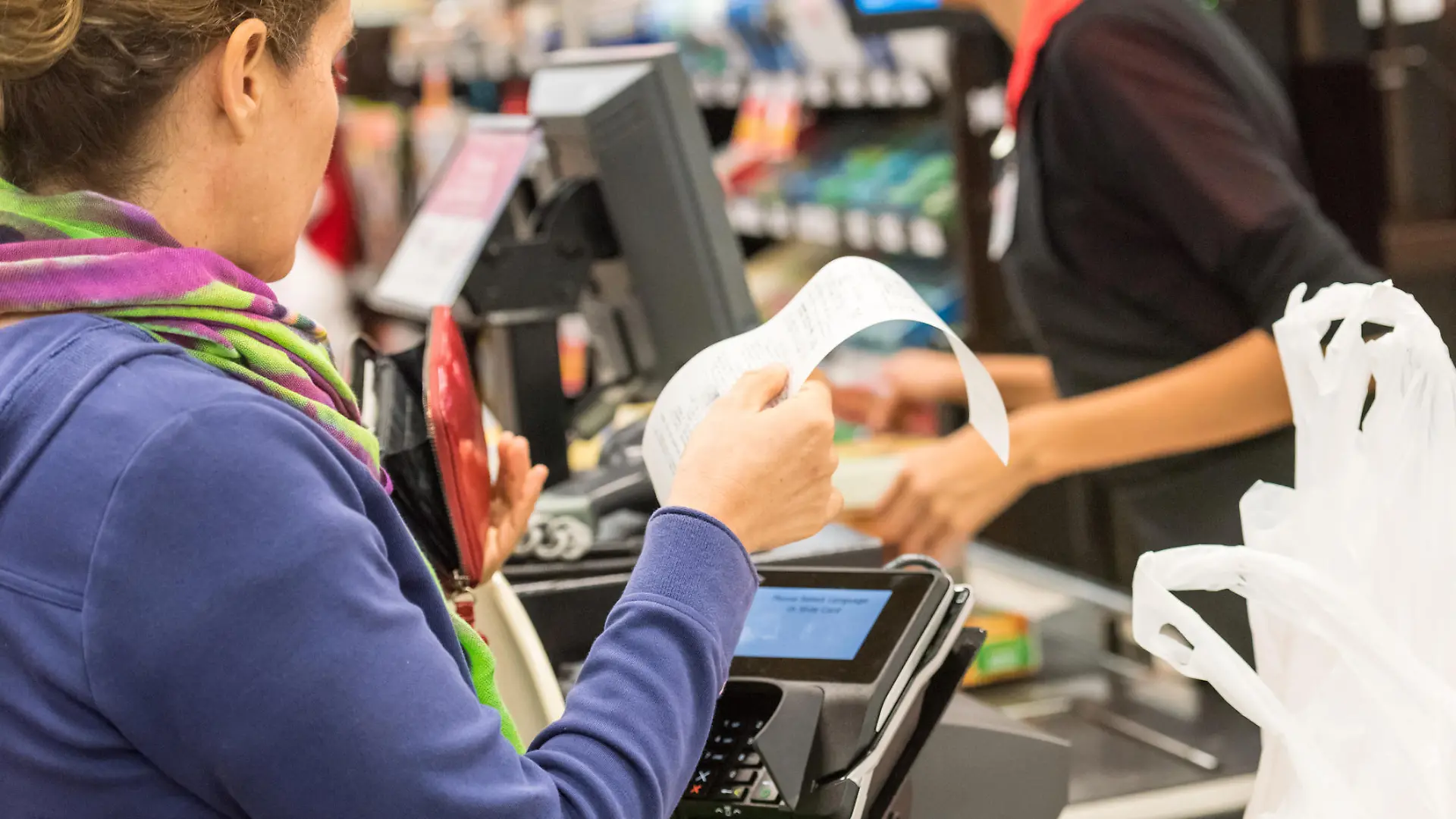 Caucasian woman electronic signing her bill at the supermarket