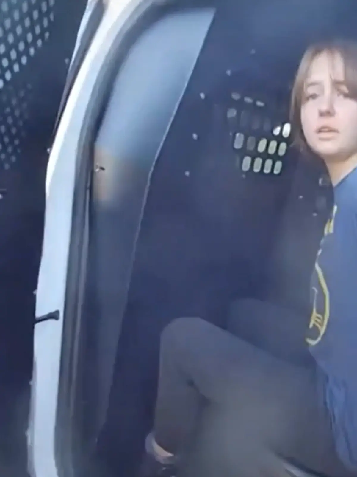 Ein Mädchen gefesselt in einem Polizeiauto. 
