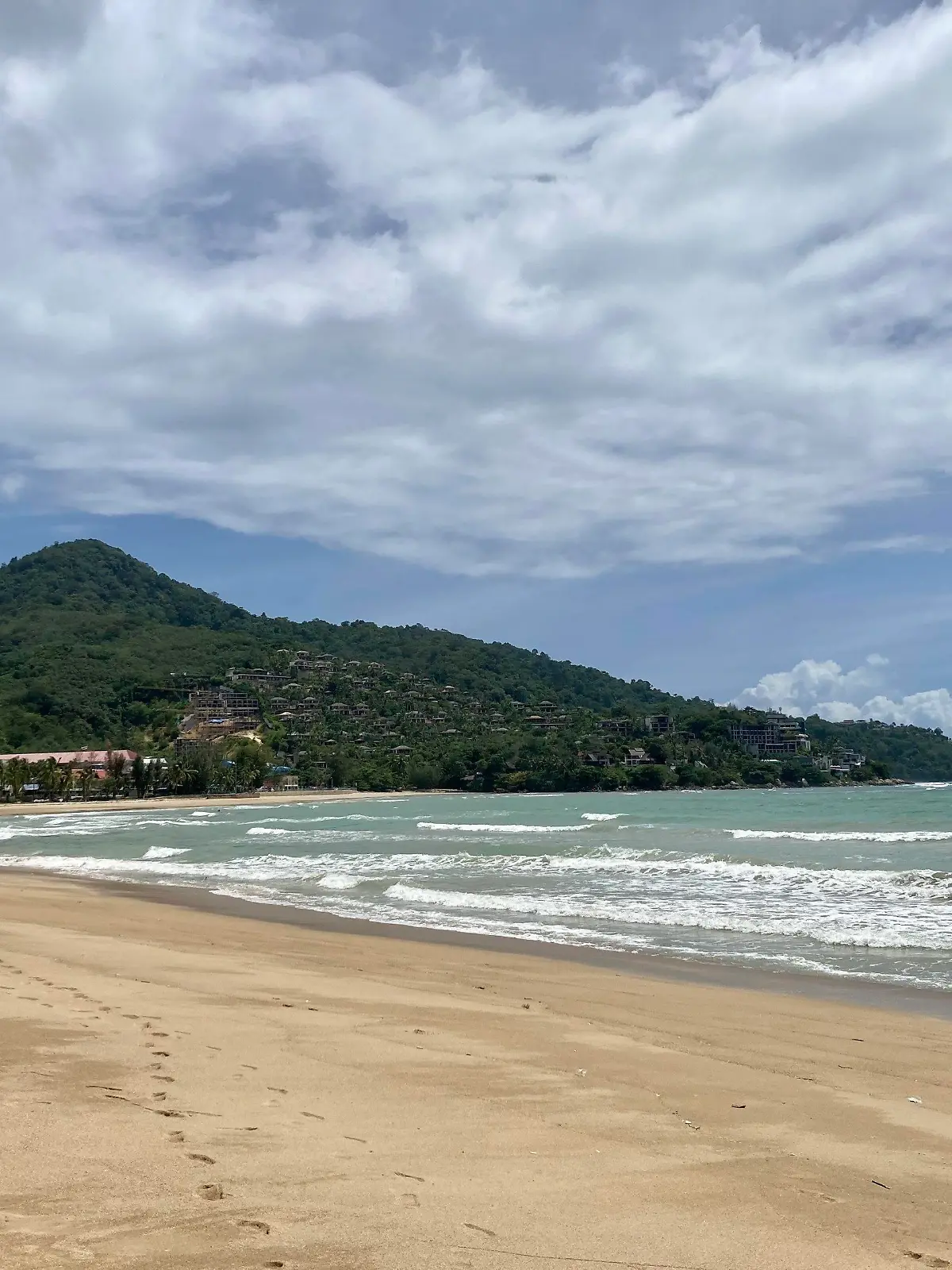 ARCHIV - 08.08.2021, Thailand, Kamala Beach: Wenige Wolken verdecken den blauen Himmel über dem Strand Kamala Beach auf Phuket. Vor einem Strand der thailändischen Urlaubsinsel Phuket ist ein achtjähriges Kind von einem Raubfisch attackiert und schwer am Bein verletzt worden. Den Rettungsdiensten zufolge könnte es sich entweder um einen großen Barrakuda oder um einen Hai gehandelt haben. (zu dpa «Achtjähriger auf Phuket von Fisch attackiert - Hai oder Barrakuda?») Foto: Carola Frentzen/dpa +++ dpa-Bildfunk +++