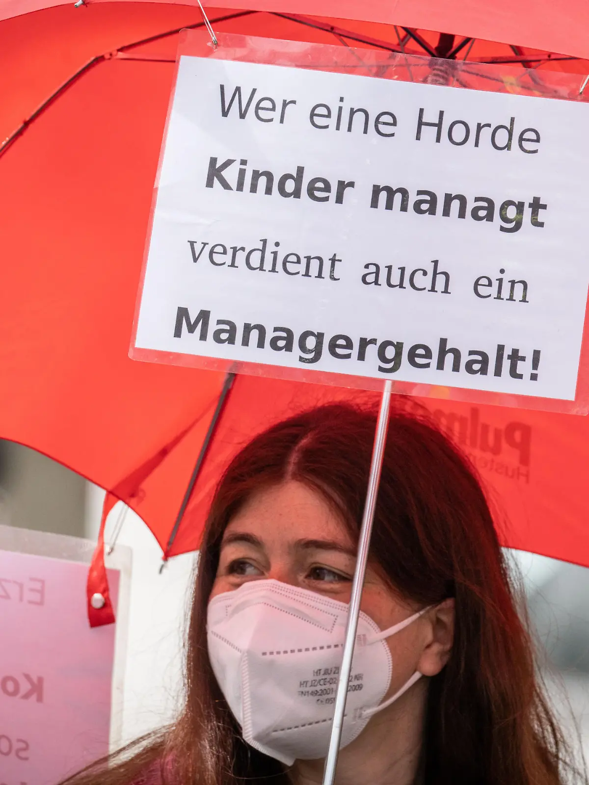 Eine Demonstrantin trägt bei einem Protestmarsch durch die Friedberger Innenstadt einen Regenschirm mit einem Plakat und der Aufschrift "Wer eine Horde Kinder managt verdient auch ein Managergehalt". Die Gewerkschaft Verdi hatte zu weiteren Warnstreiks in hessischen Kindertagesstätten sowie in der Sozialarbeit und der Behindertenhilfe aufgerufen. Hintergrund des Tarifkonflikts sind die laufenden Verhandlungen für die bundesweit rund 330 000 Kita-Erzieherinnen und -Erzieher sowie von Angehörigen anderer sozialer Berufe im kommunalen Bereich.