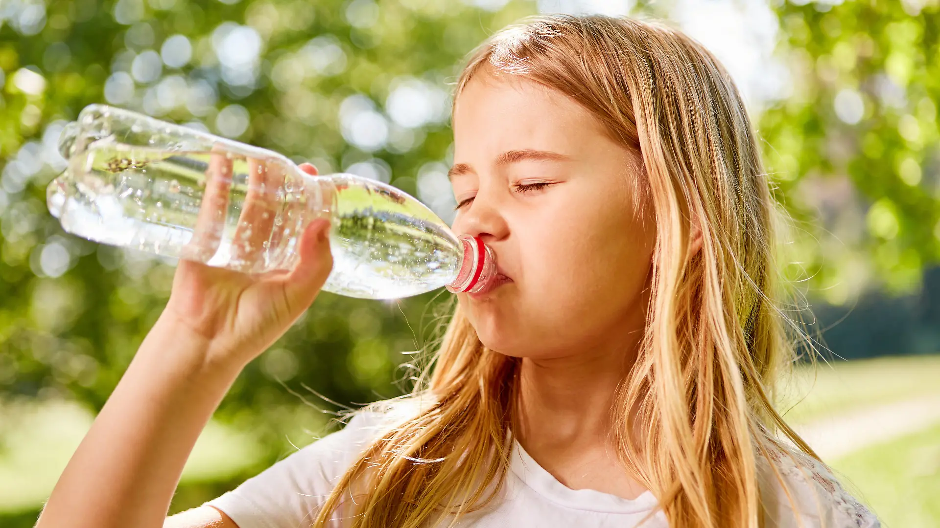 Ein Mädchen trinkt Wasser aus einer Plastikflasche. 