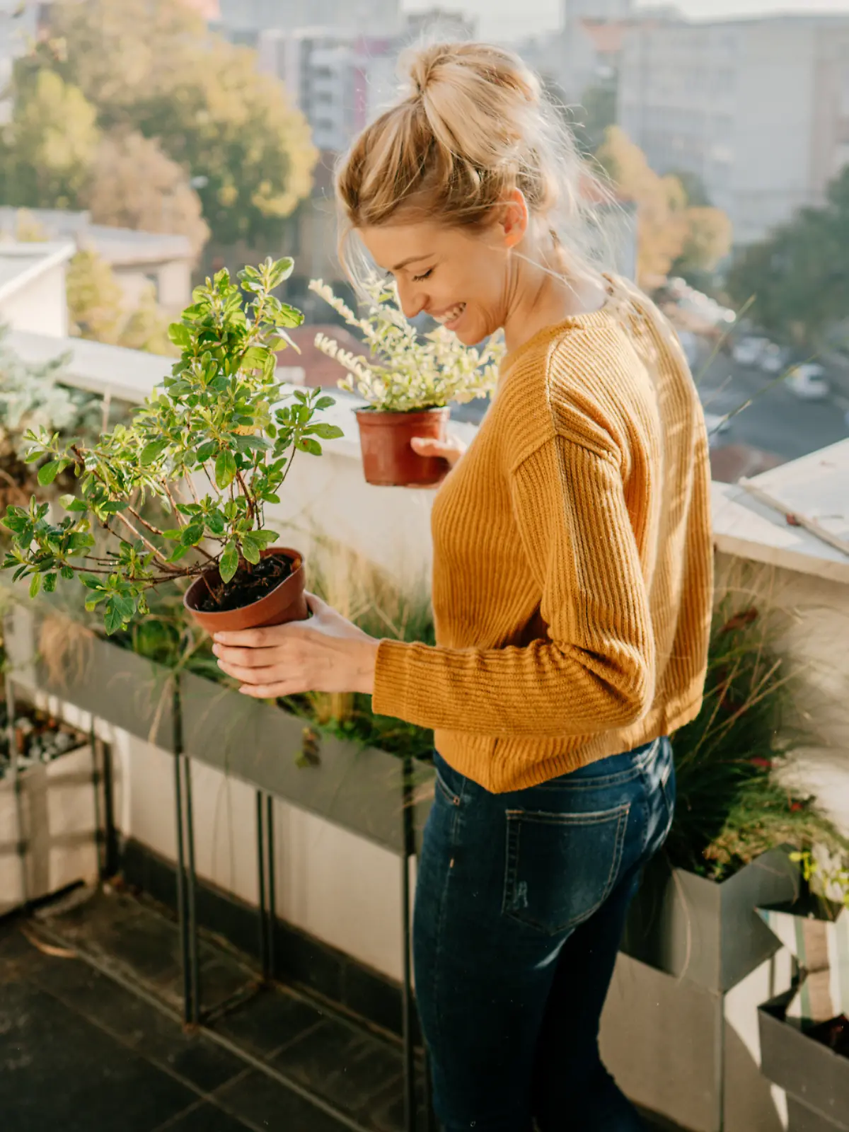 Junge Frau bepflanzt Balkon herbstlich. 