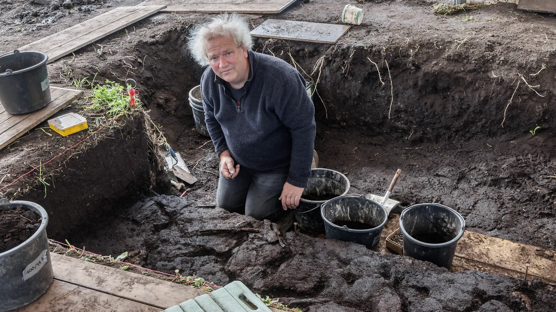 Grabungsleiter Harald Lübke kniet in einem Grabungsschnitt im Duvenseer Moor.