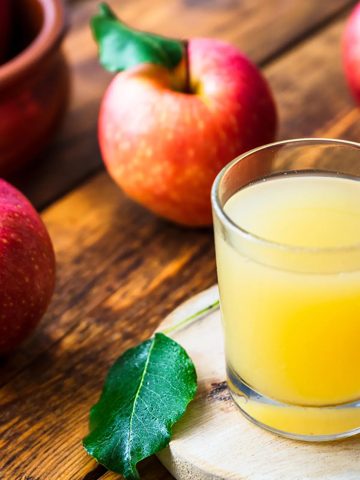 Naturtrüber Apfelsaft im Glas neben Äpfeln