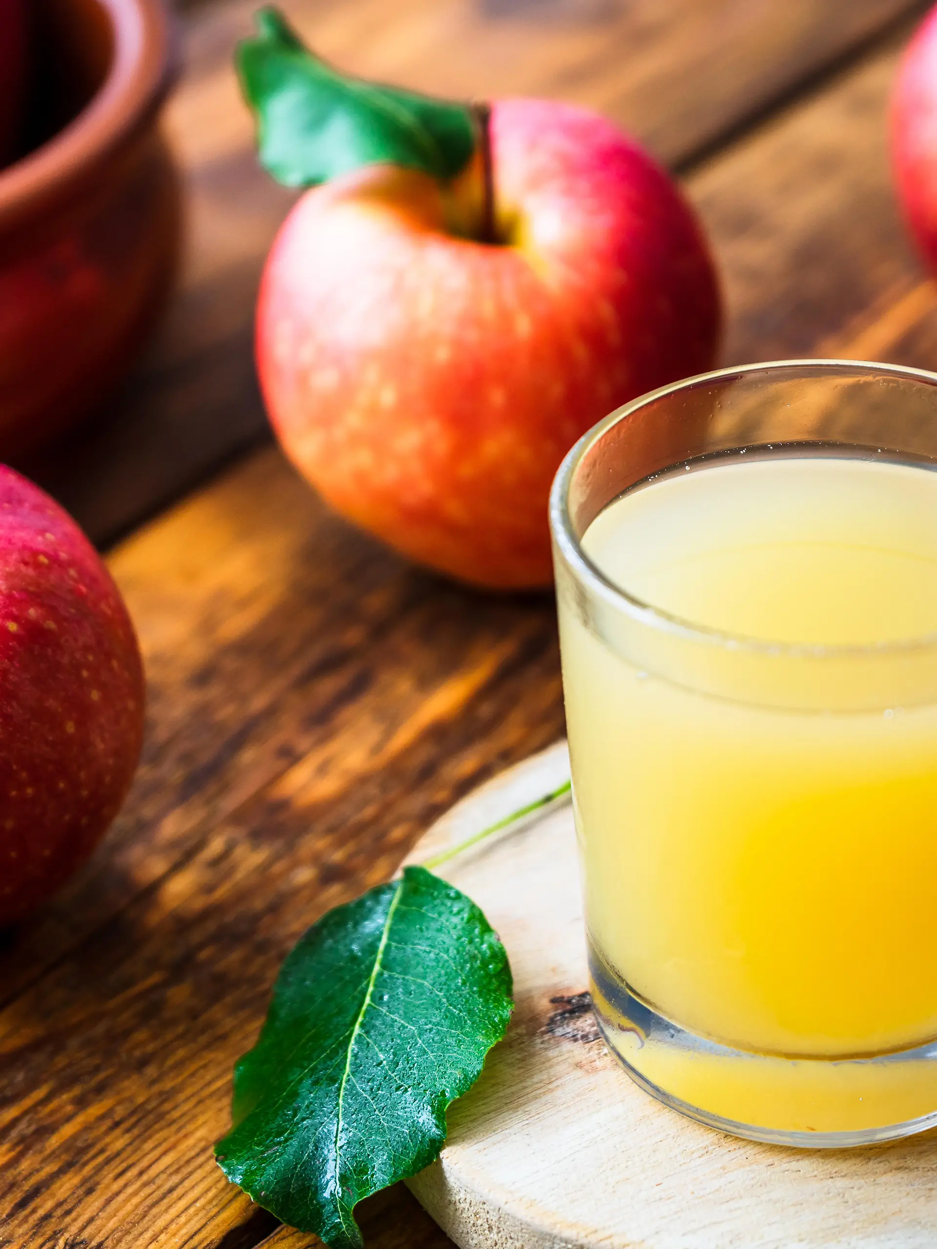 Naturtrüber Apfelsaft im Glas neben Äpfeln