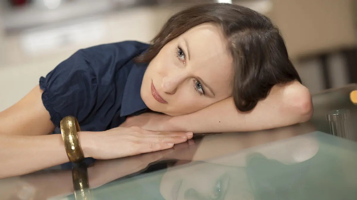 Junge Frau lehnt gedankenverloren am Glastisch - thoughtfully woman wt home | Verwendung weltweit, Keine Weitergabe an Wiederverkäufer.