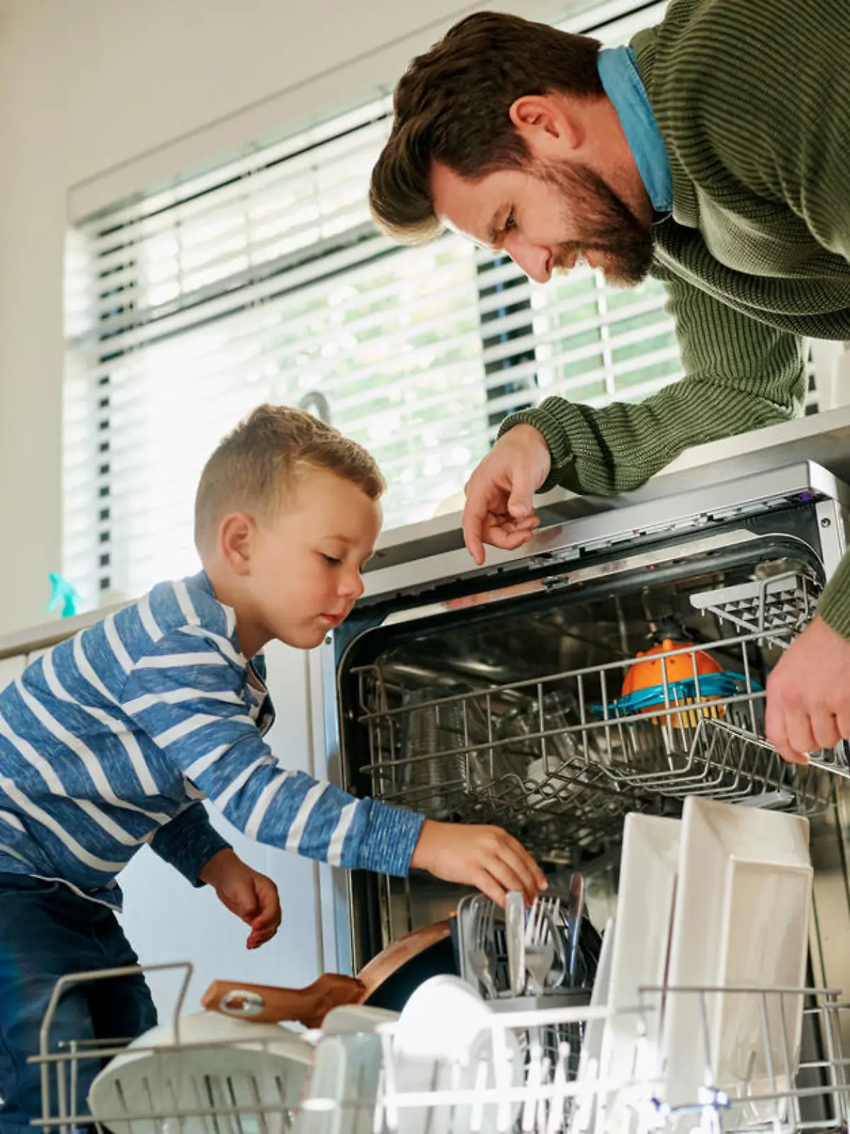Vater und Sohn räumen Spülmaschine ein