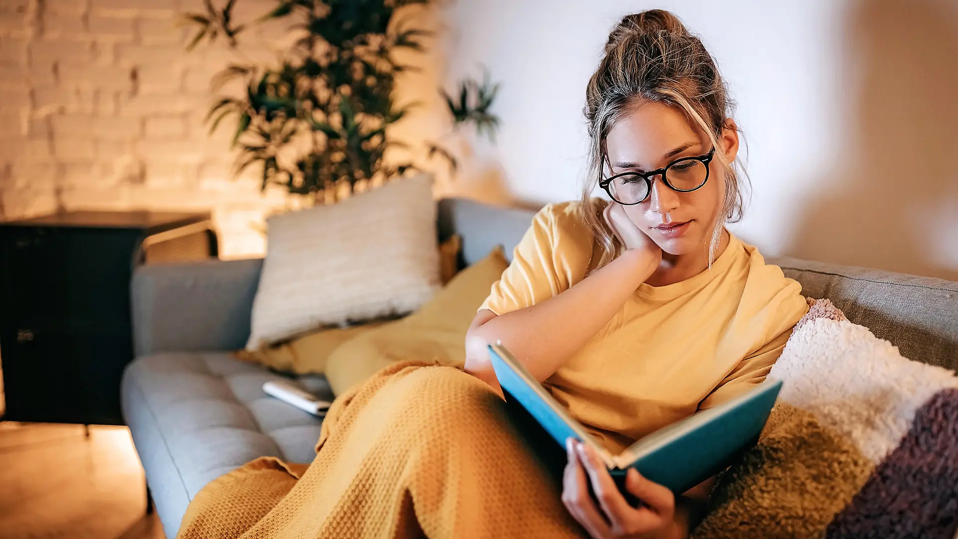 Young women reading book at home in sofa