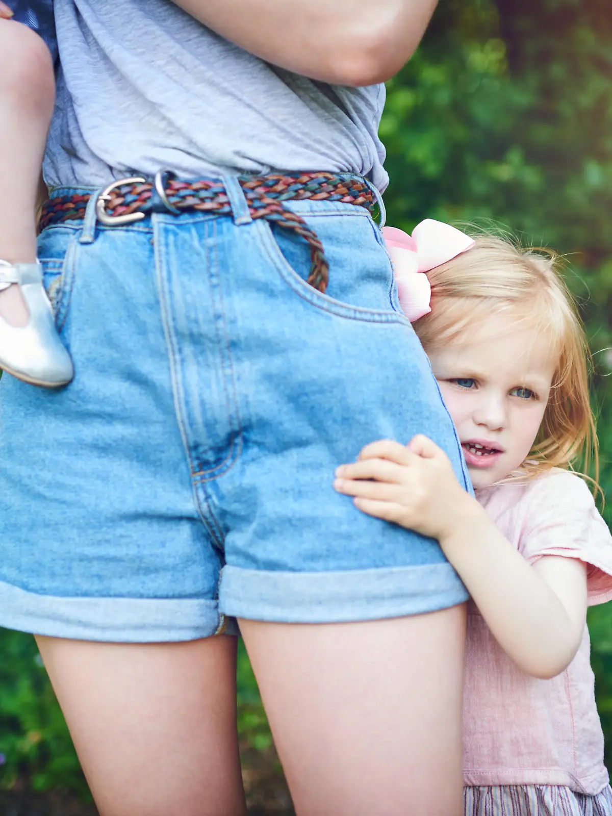 Shot of a little girl holding onto her mother during a day outdoors