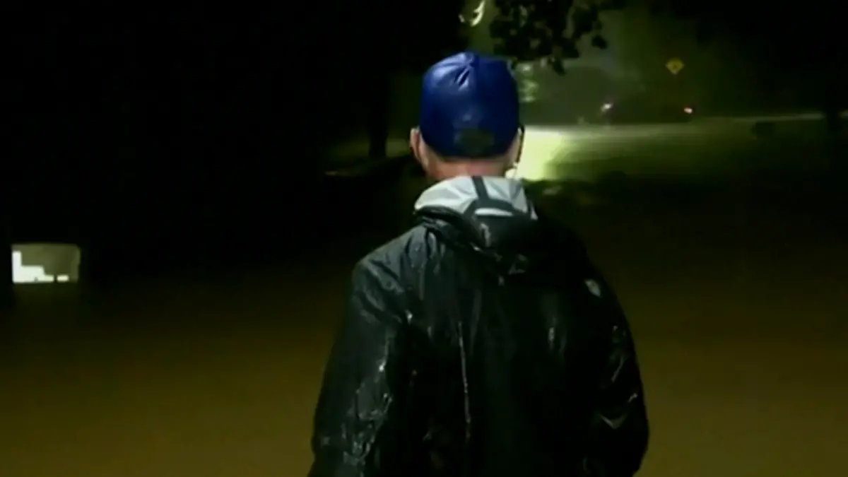 Ein Wetter-Reporter steht im Wasser.