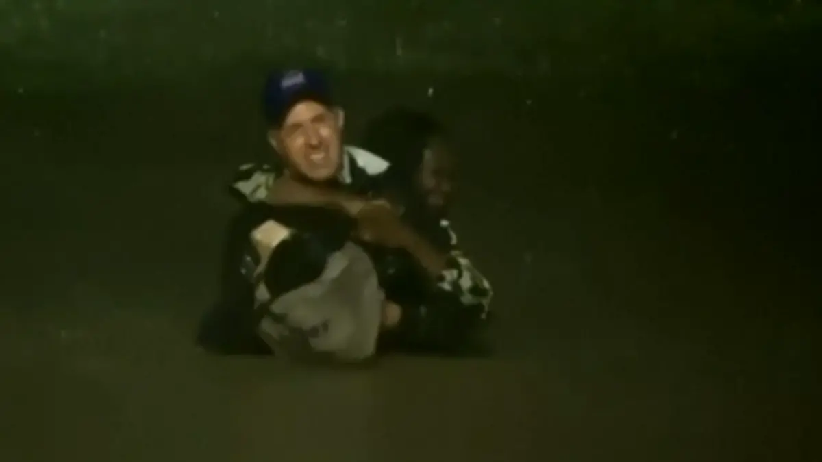 Ein Mann trägt eine Frau Huckepack durchs Wasser.