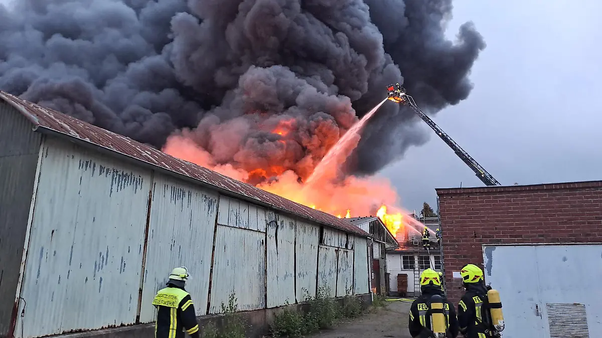 29.06.2023, Niedersachsen, Varel: Einsatzkräfte der Feuerwehr löschen den Brand in einer Porzellanfabrik. In einer Porzellanfabrik in Varel (Landkreis Friesland) ist ein Feuer ausgebrochen. Mehrere Lagerhallen stehen seit Donnerstagabend auf dem Gelände der Fabrik in Vollbrand, wie ein Polizeisprecher sagte. Über dem Firmengelände steigt eine riesige Rauchwolke auf. Die Polizei bat die Anwohnenden, Türen und Fenster geschlossen zu halten. Die Feuerwehr ist mit zahlreichen Lösch- und Rettungsfahrzeugen vor Ort. Ob es Verletzte gab, war zunächst nicht bekannt. Foto: Steve Hamann/Nord-West-Media/dpa +++ dpa-Bildfunk +++
