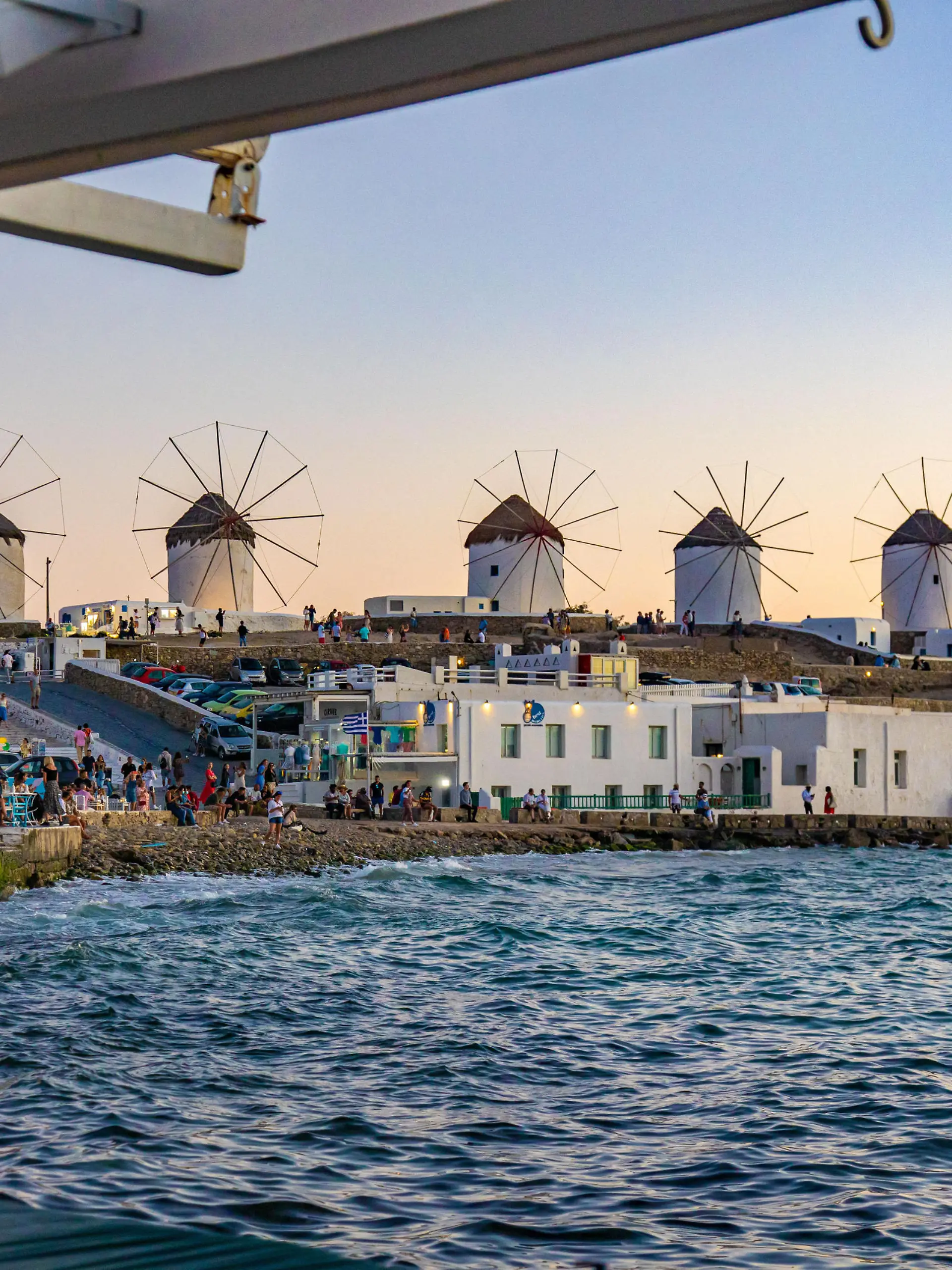 The iconic windmills of Mykonos island as seen from Little Venice with tourists at the bars, cafes and restaurants. Mykonos is an island in Greece in the Aegean sea. There are 16 windmills on the island, 5 of them above Chora, the main town in the island. The windmills were built in the 16th century from the Venetians but their constructions continued until the 20th century. Sunset with people at the windmills in Mykonos. Tourists enjoy a beautiful sunset during the magic hour at Mykonos island in Greece. The Greek island of Myconos is a popular glamorous Mediterranean travel destination for holidays in the Cyclades, Aegean Sea with the iconic whitewashed buildings, the sandy beaches and famous party at the beach bars. The tourism and travel industry had a negative impact in the business and local economy sector due to the Covid-19 Coronavirus pandemic. Mykonos island, Greece(Photo by Nicolas Economou/NurPhoto)