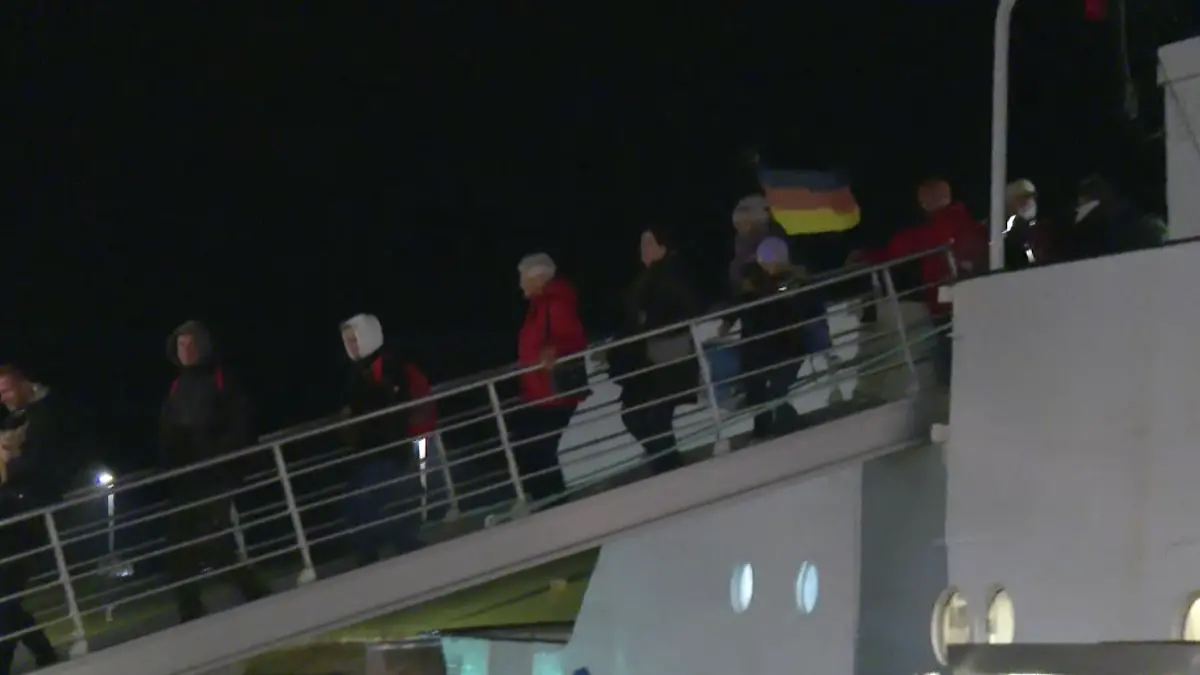 Menschen gehen über eine Brücke von Bord eines Schiffes.
