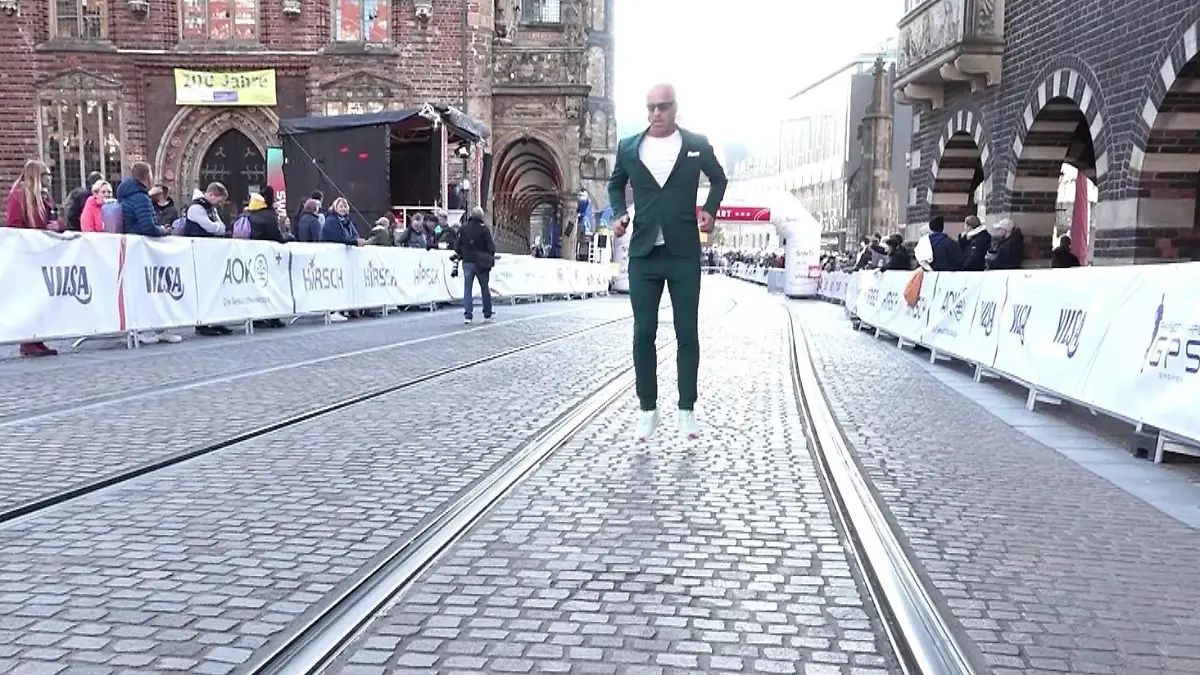 Mit kleinen Sprüngen hüpft Emin da Silva ins Ziel und das sogar im Anzug.