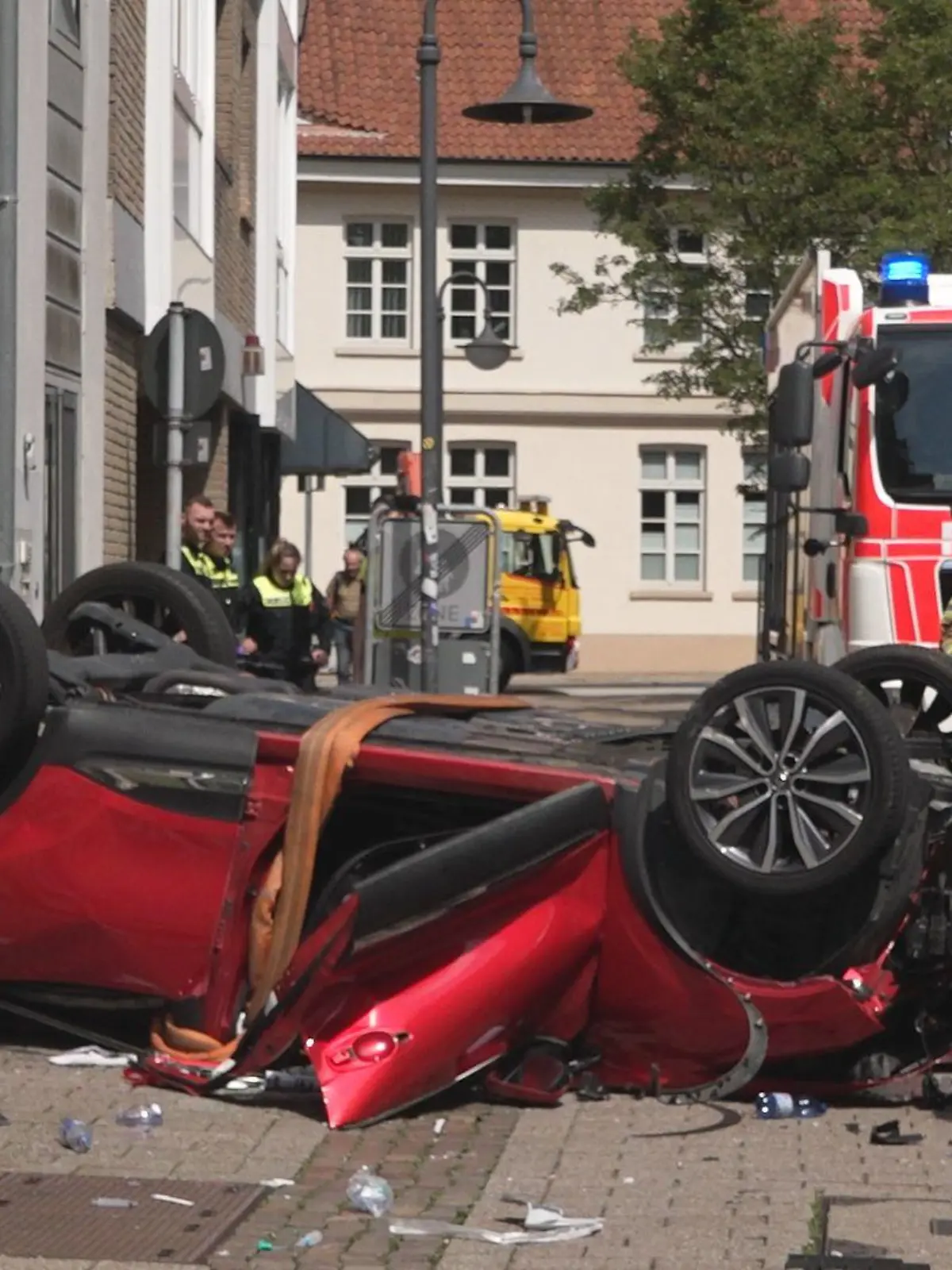 30.06.2023, Oldenburg: Vor einem Parkhaus liegt ein Auto auf dem Dach. Der Wagen war aus dem vierten Stock des Parkhauses auf die Straße gefallen.     (zu dpa: «81-Jährige stürzt in Oldenburg mit Auto von Parkdeck und stirbt») Foto: Andre van Elten/TV7News/dpa +++ dpa-Bildfunk +++
