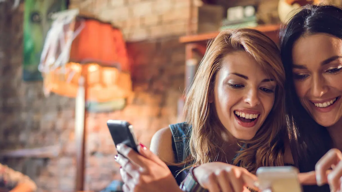 Happy women using their mobile phones while relaxing in a cafe.