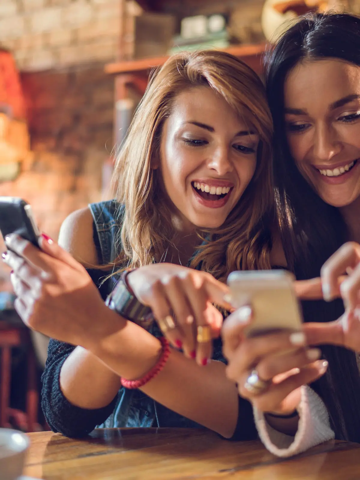 Happy women using their mobile phones while relaxing in a cafe.