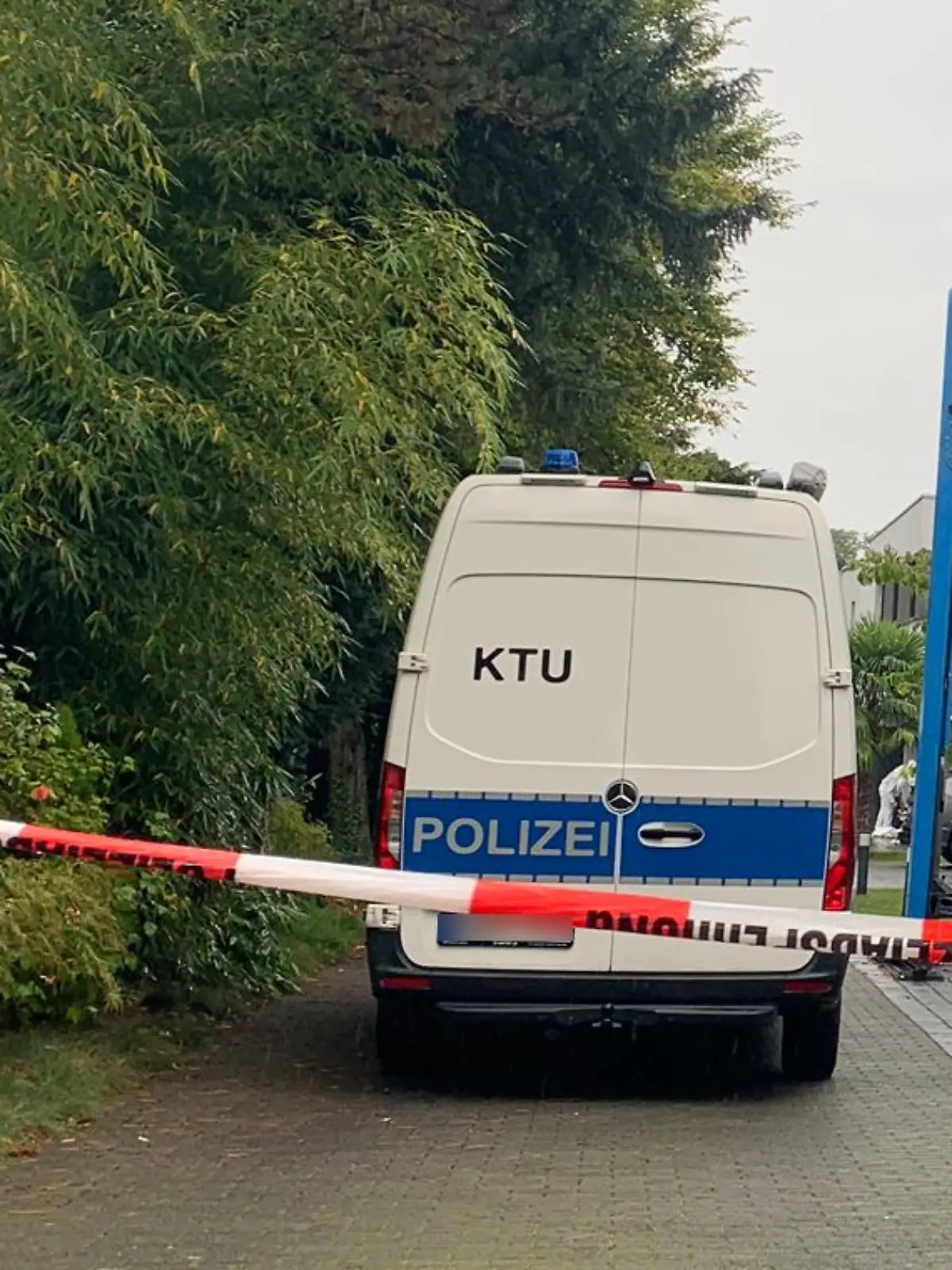Die Polizei steht in einer Straße vor mehreren Häusern. In einer dieser Villen hat sich ein Mord ereignet. 
