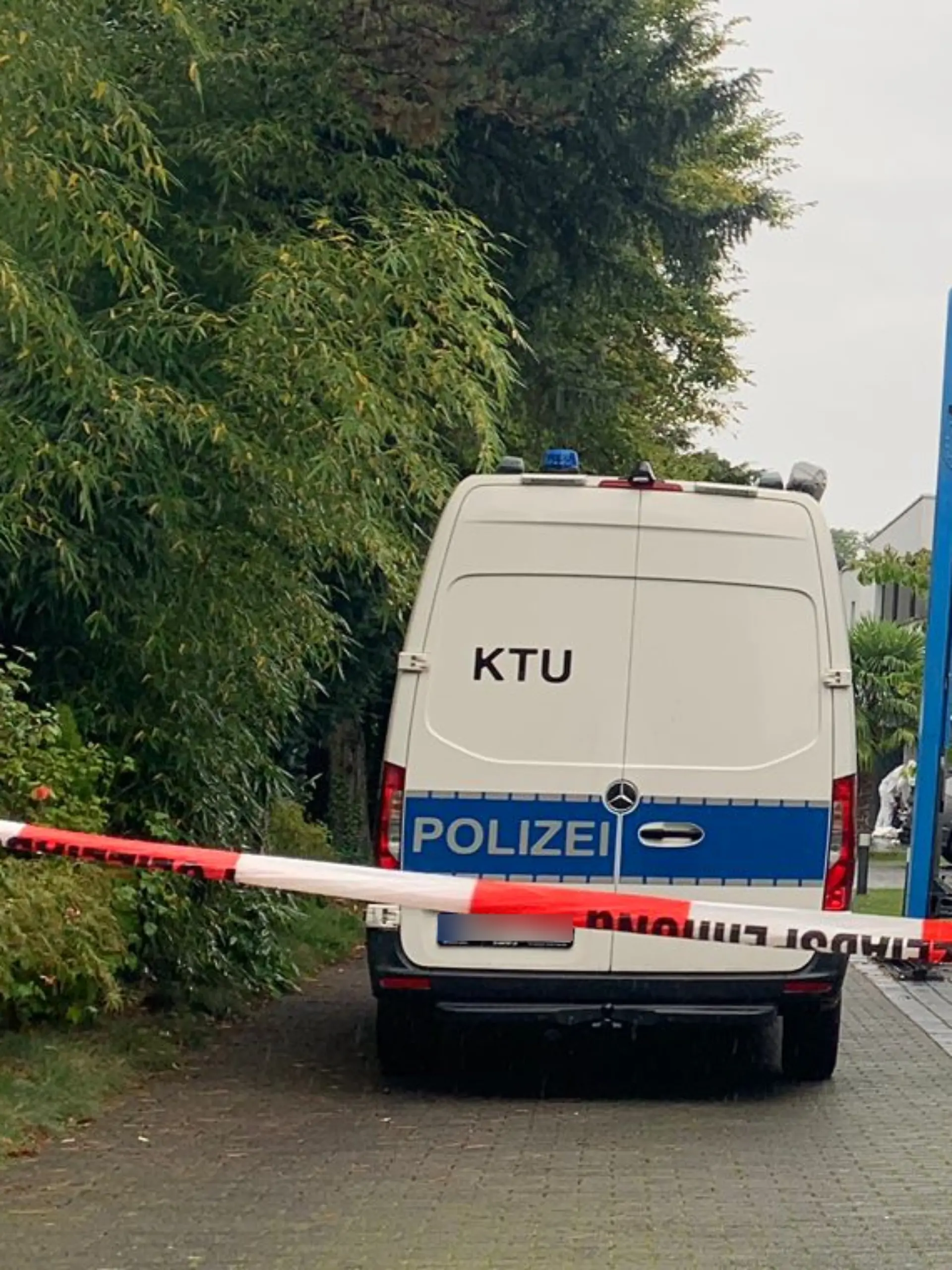 Die Polizei steht in einer Straße vor mehreren Häusern. In einer dieser Villen hat sich ein Mord ereignet. 