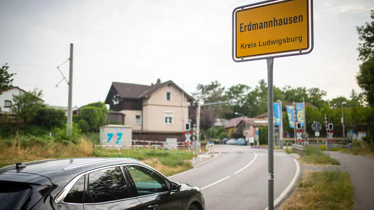 29.06.2023, Baden-Württemberg, Erdmannhausen: Ein Auto fährt am Ortseingangsschild von Erdmannhausen vorbei. Unter anderem für das übermäßig laute Schließen von Autotüren und das unnötige Laufenlassen von Motoren kann es in der baden-württembergischen Gemeinde Erdmannhausen bald Bußgelder geben. Foto: Christoph Schmidt/dpa +++ dpa-Bildfunk +++